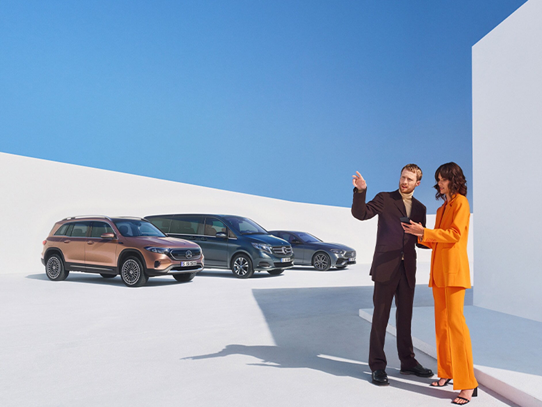 Egy férfi és egy nő több Mercedes-Benz gépkocsi előtt.