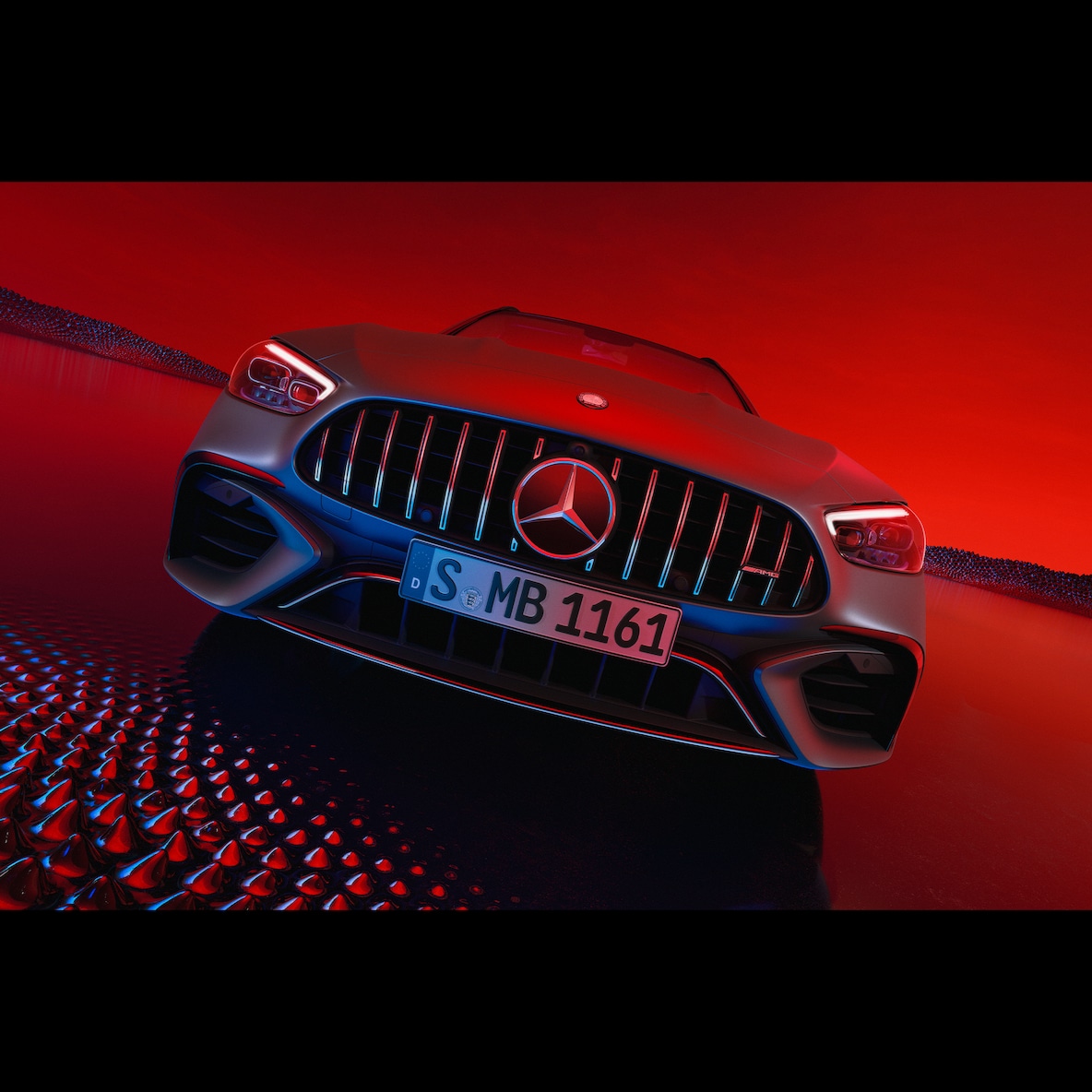 A Mercedes-AMG C 63 S E PERFORMANCE elölnézetből egy piros háttér előtt.