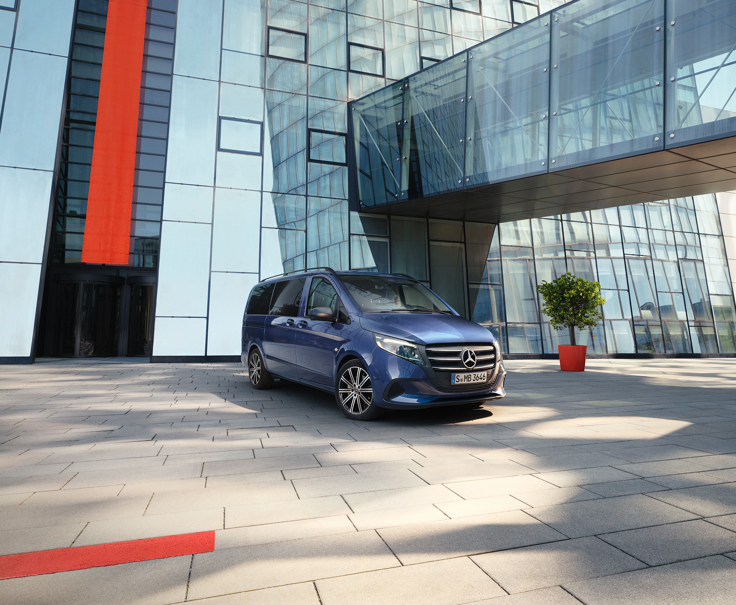 Vito Tourer | Buszlimuzinok és lakóautó modellek | Mercedes-Benz buszlimuzinok Mercedes‑Benz Vito Tourer tolóajtóval egy modern épület előtt.