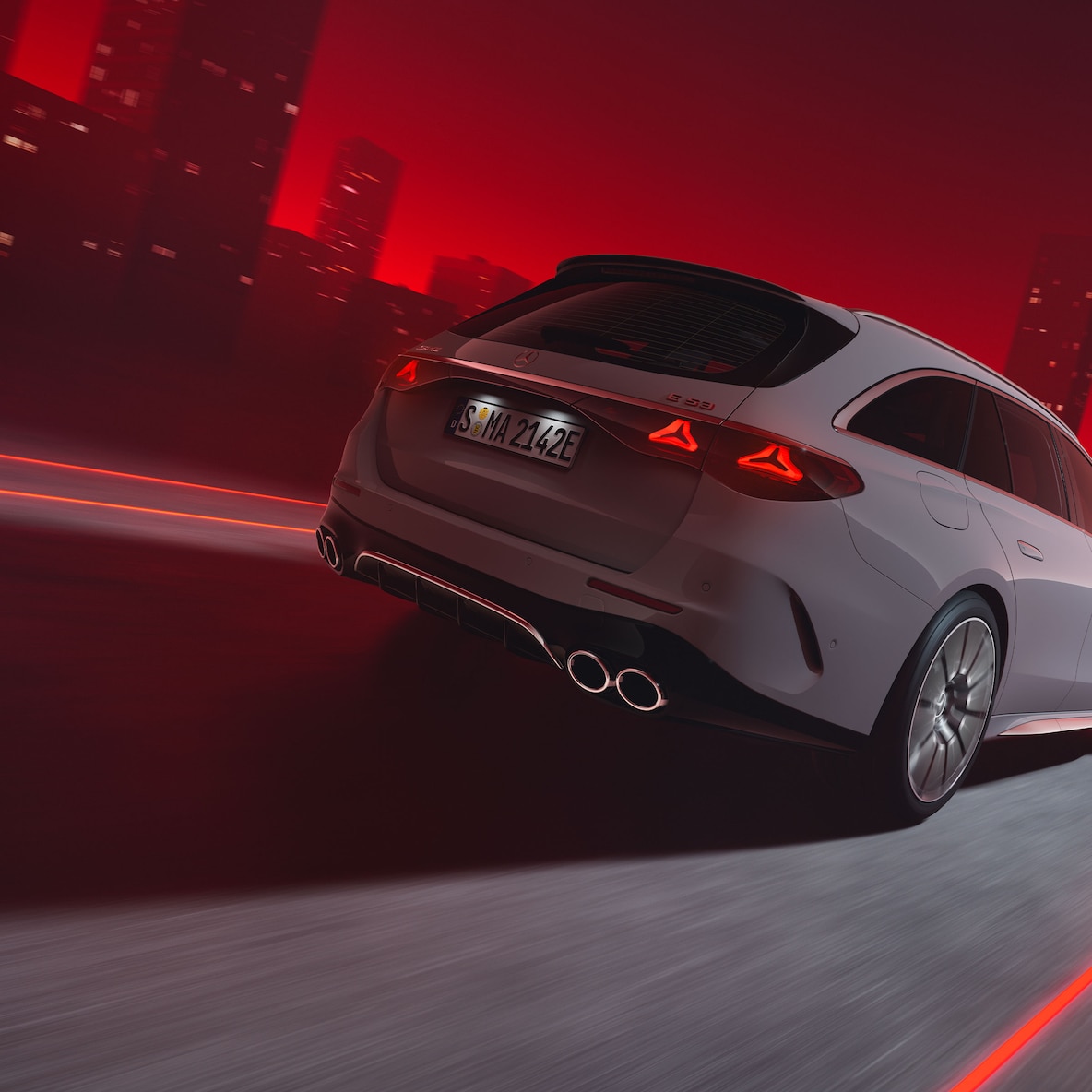 Egy Mercedes-AMG E 53 HYBRID 4MATIC+ T-modell hátulnézetből menetközben piros háttér előtt.