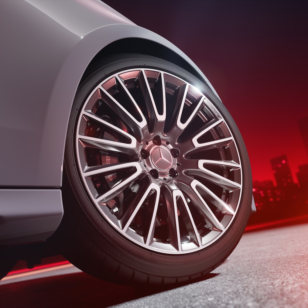 Egy AMG kovácsolt keréktárcsa közelképe pirosra festett féknyergekkel rendelkező AMG nagy teljesítményű kompozit fékrendszerrel.