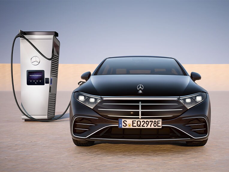A Mercedes-Benz EQS limuzin elölnézetben, nyilvános töltőállomáson töltve.
