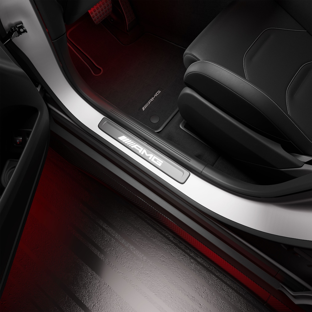 Az „AMG” feliratos megvilágított AMG küszöblécek közelképe.