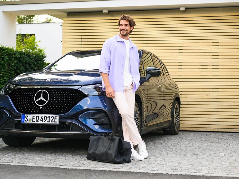 Egy ember egy Mercedes-Benz járműnek támaszkodva az eget nézi.