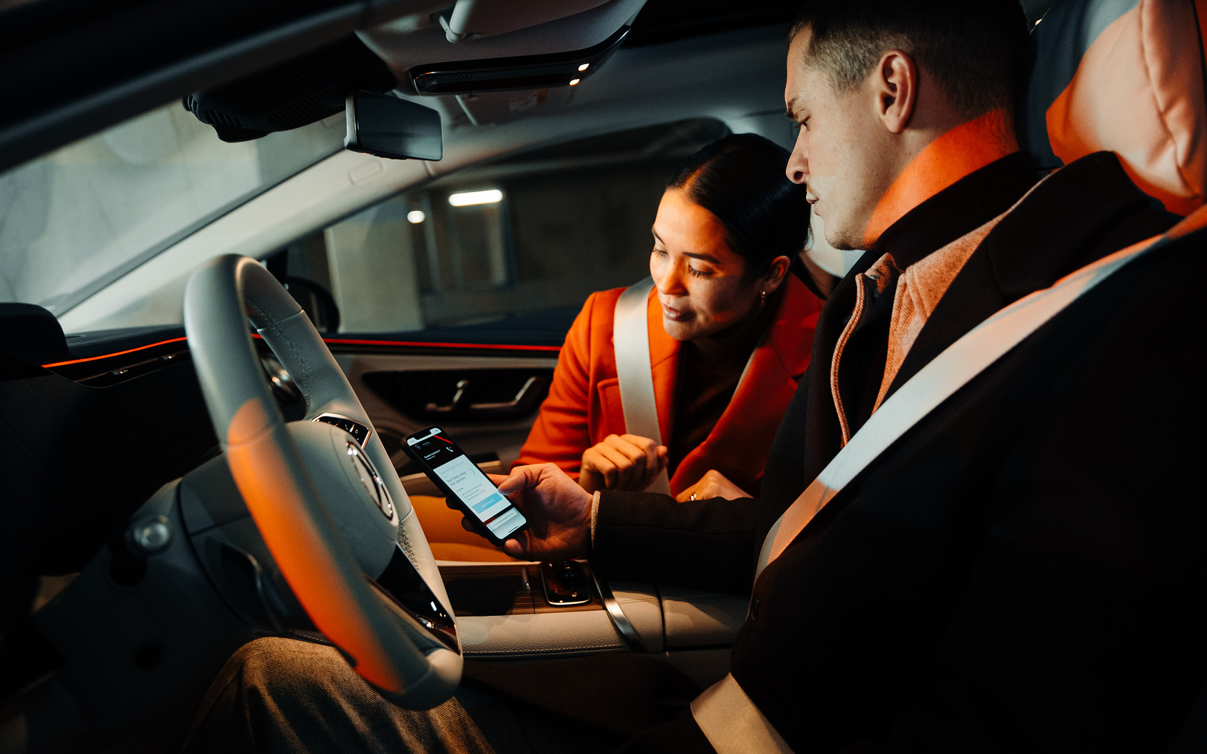 Online kárbejelentés | Mercedes-Benz Egy Mercedes-Benz járműben ülő pár okostelefonon keresztül kárbejelentést intéz.