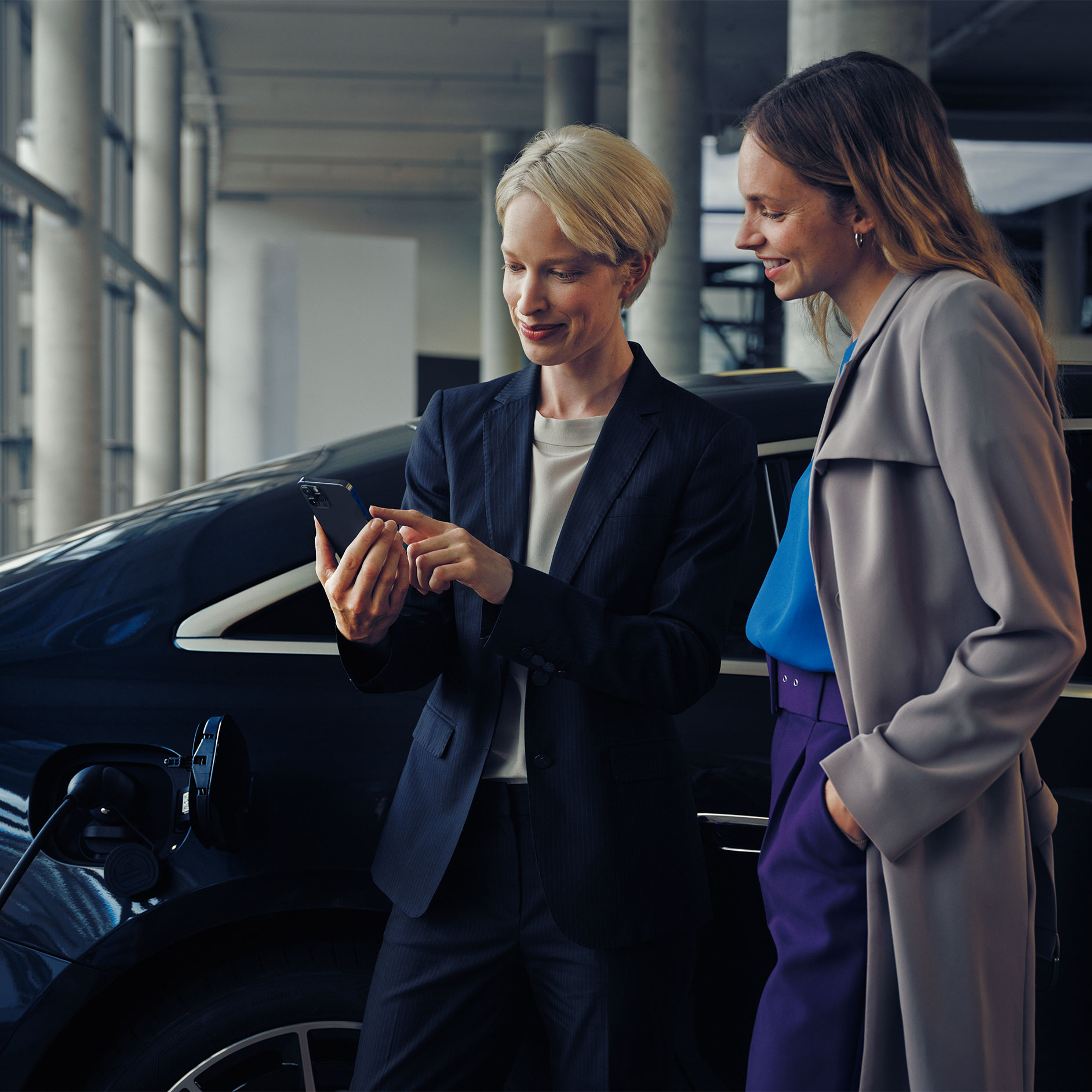 Telepítési tanácsadás | Töltés | Mercedes-Benz Két nő egy töltődő EQE limuzin előtt.