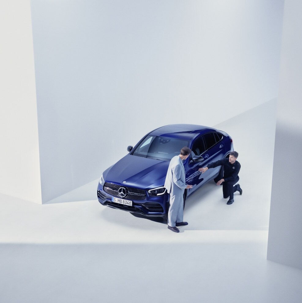 Egy nő áll a Mercedes-Benz előtt, telefonjával a kezében, és éppen telefonál