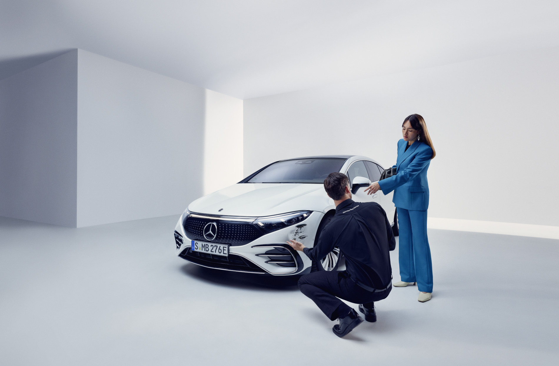 Baleseti károk javítása | Mercedes-Benz A Mercedes-Benz ügyfélszolgálatának munkatársa térdel egy sérült Mercedes-Benz mellett.