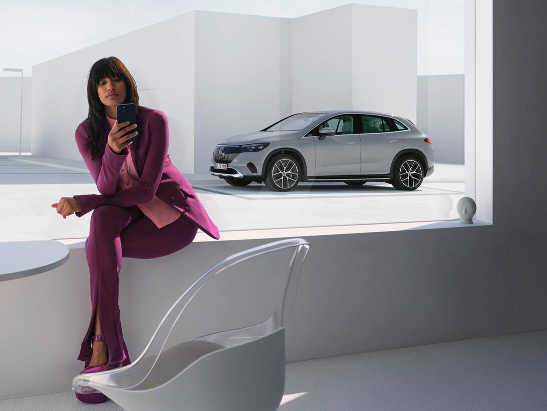 Egy hölgy telefonál Mercedes-Benz modellje előtt