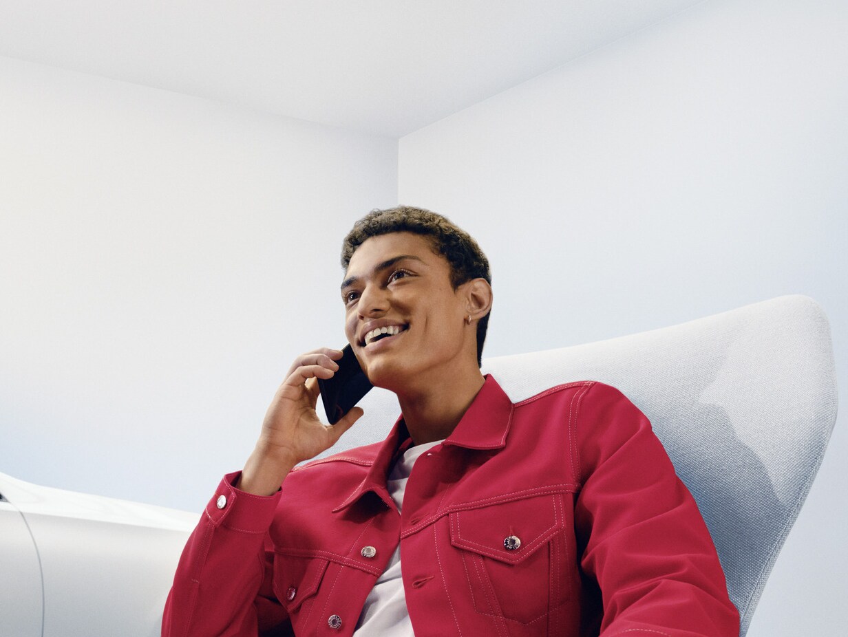 Egy hölgy telefonbeszélgetés közben Mercedes-Benz modellje előtt