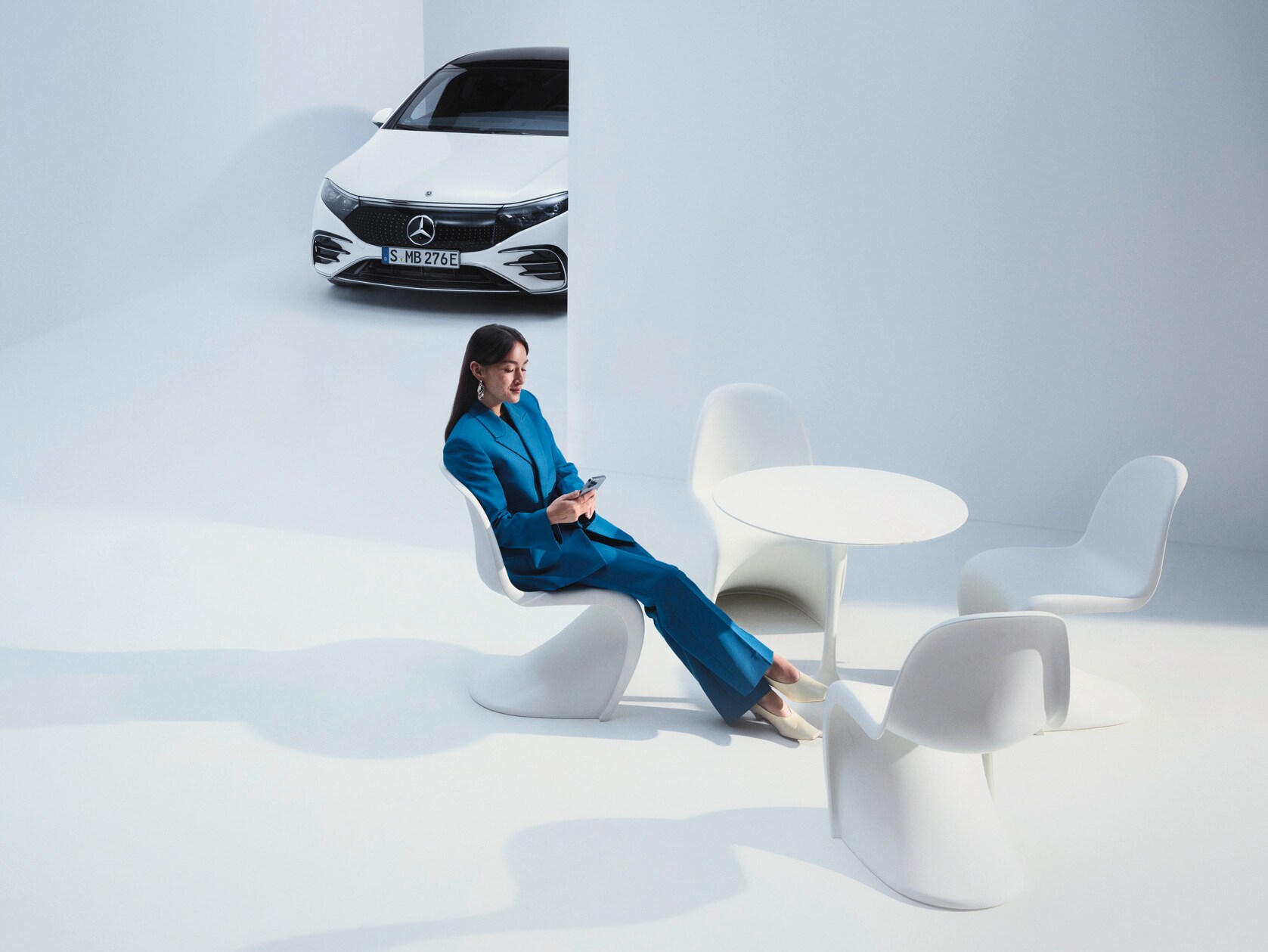 Egy hölgy telefonbeszélgetés közben Mercedes-Benz modellje előtt