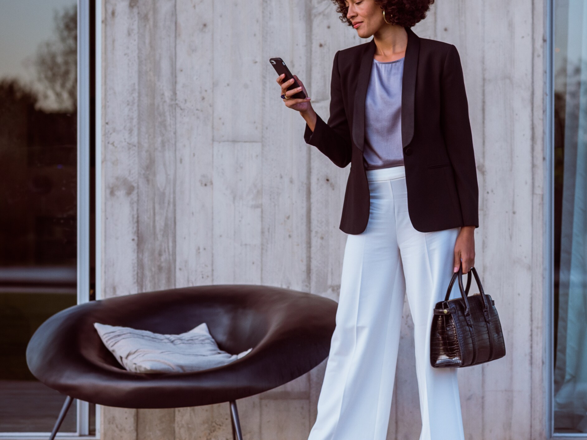 Egy nő okostelefonon, a Mercedes alkalmazáson és a Mercedes me ID-n keresztül csatlakozik Mercedes-Benz autójához.