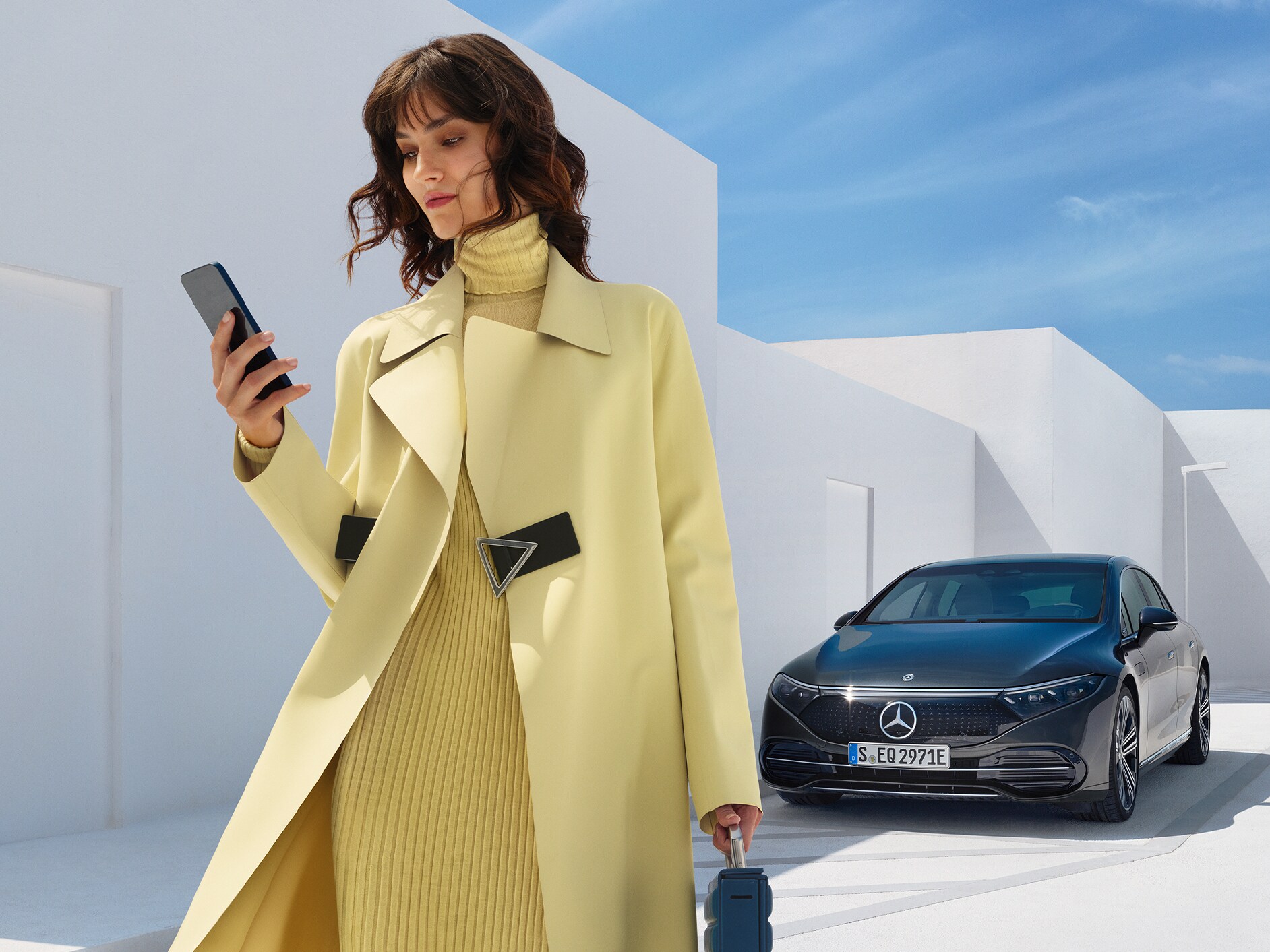 Egy hölgy áll egy Mercedes-Benz EQS limuzin előtt.