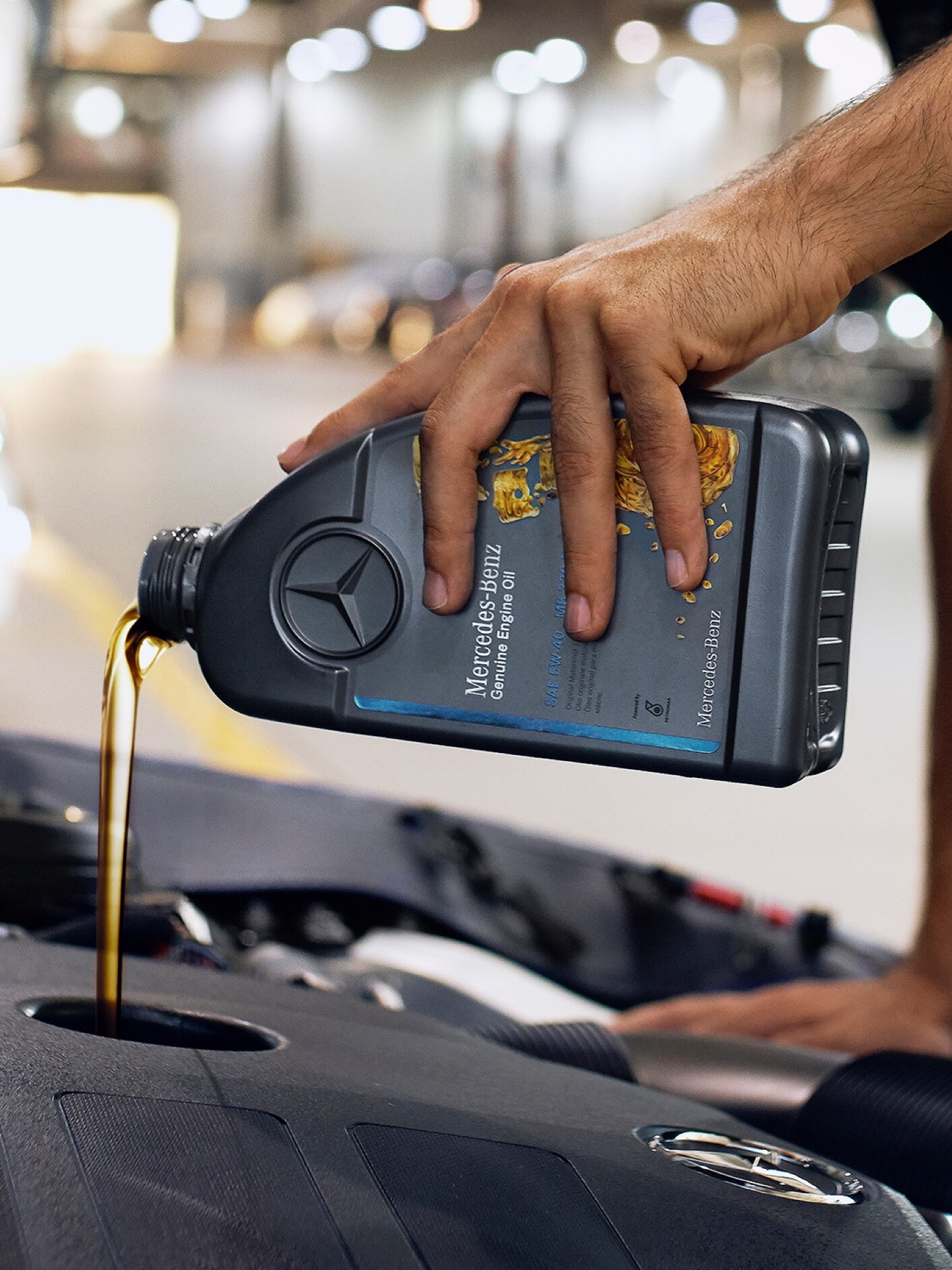 Egy személy, aki motorolajat önt a Mercedes-Benz járműbe.