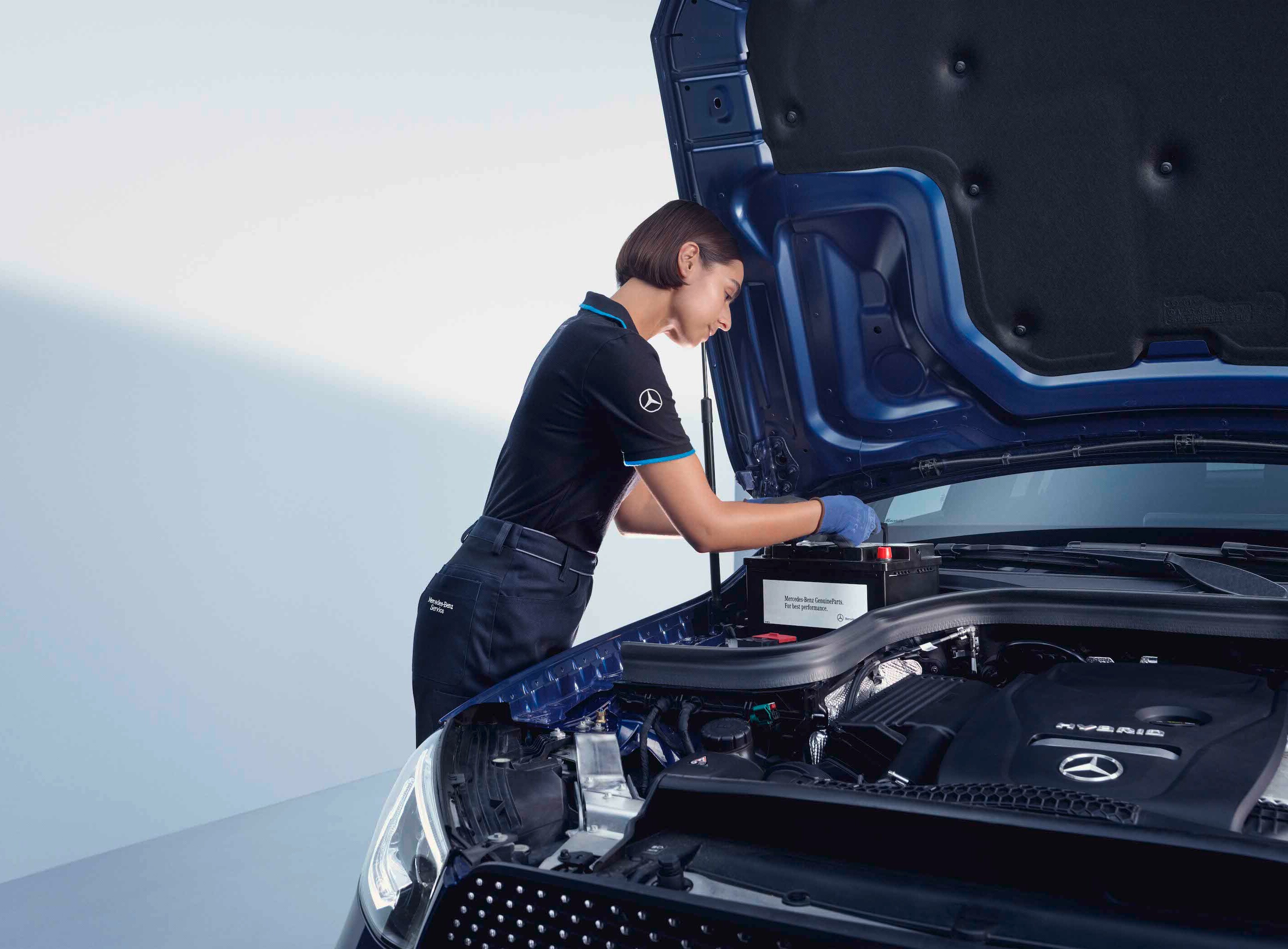 Egy szerelő egy Mercedes-Benz modell nyitott motorháztetője fölé hajol.