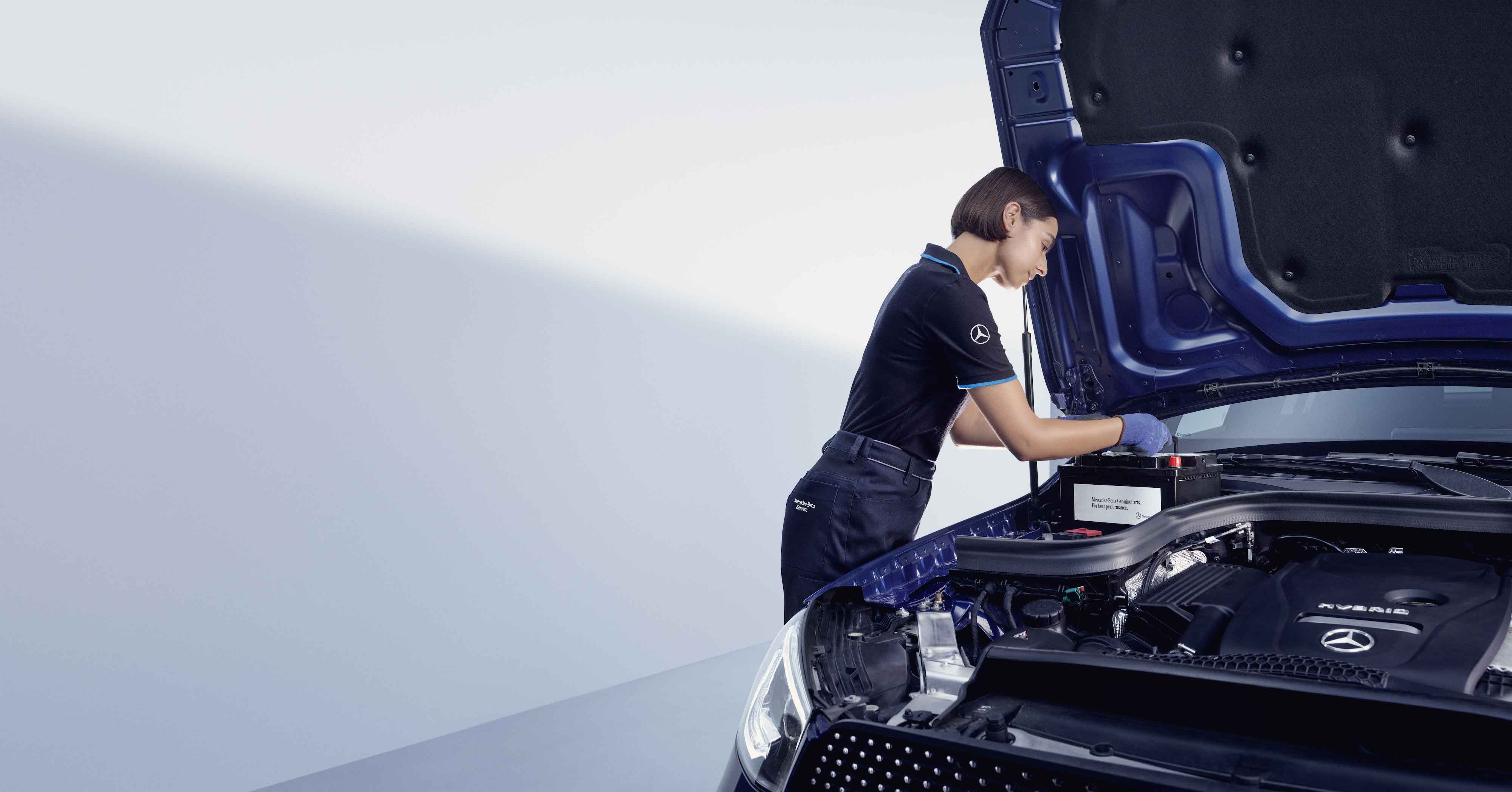 Eredeti alkatrészek | Mercedes-Benz Egy szerelő egy Mercedes-Benz modell nyitott motorháztetője fölé hajol.