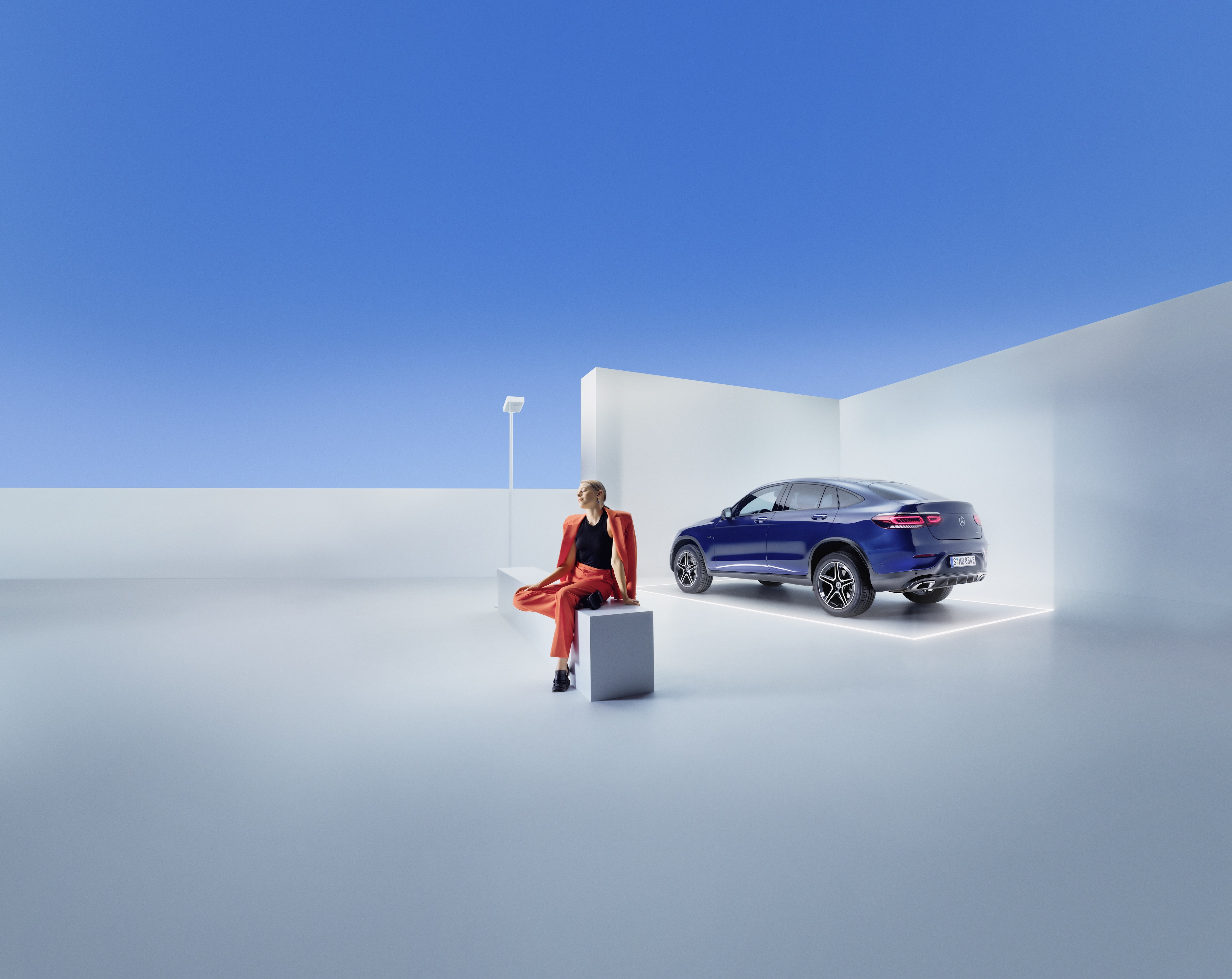 Szervizszerződések | Mercedes-Benz Egy nő ül egy padon egy Mercedes-Benz előtt.