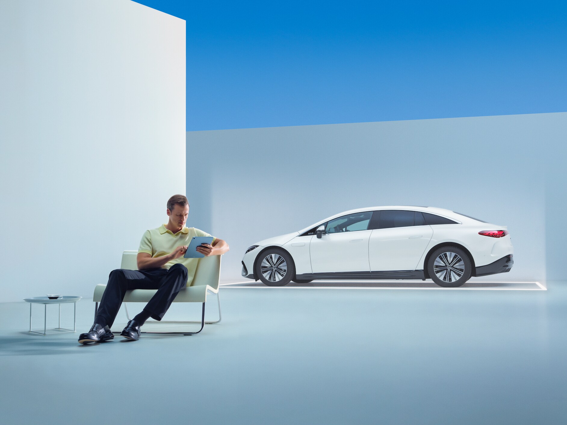 Egy személy a Mercedese előtt ül a tabletjével.