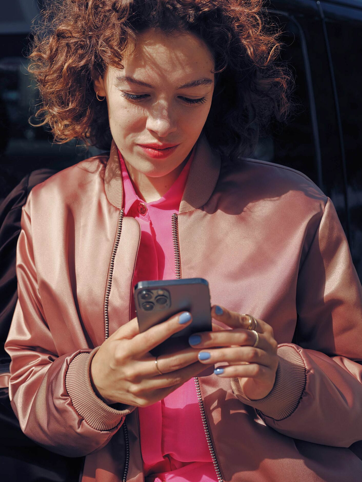 Egy nő egy mobiltelefonon, egy fekete Mercedes-Benz EQV-Van mellett