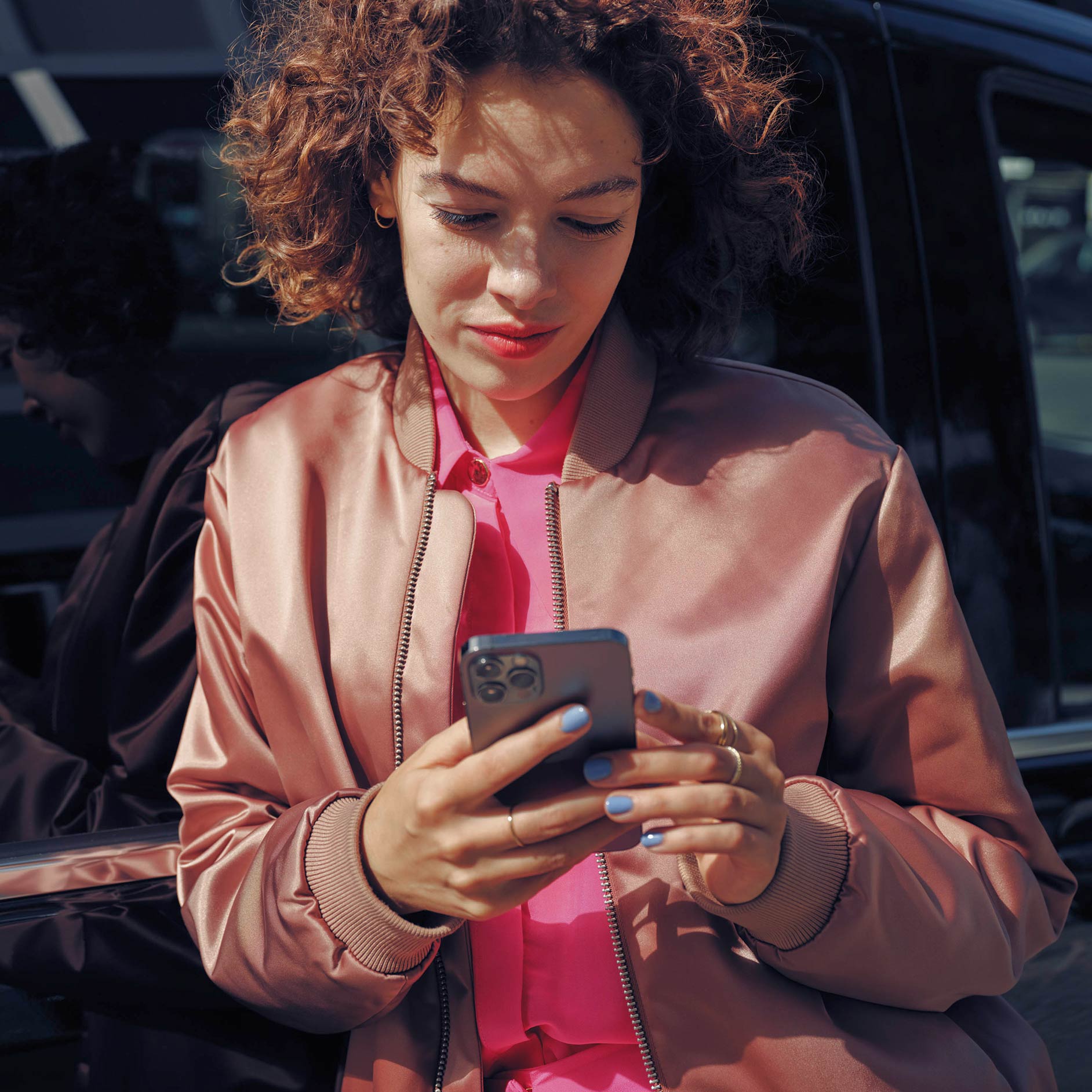 Bérlés | Pénzügyi szolgáltatások | Mercedes-Benz Transzporterek Egy nő egy mobiltelefonon, egy fekete Mercedes-Benz EQV-Van mellett