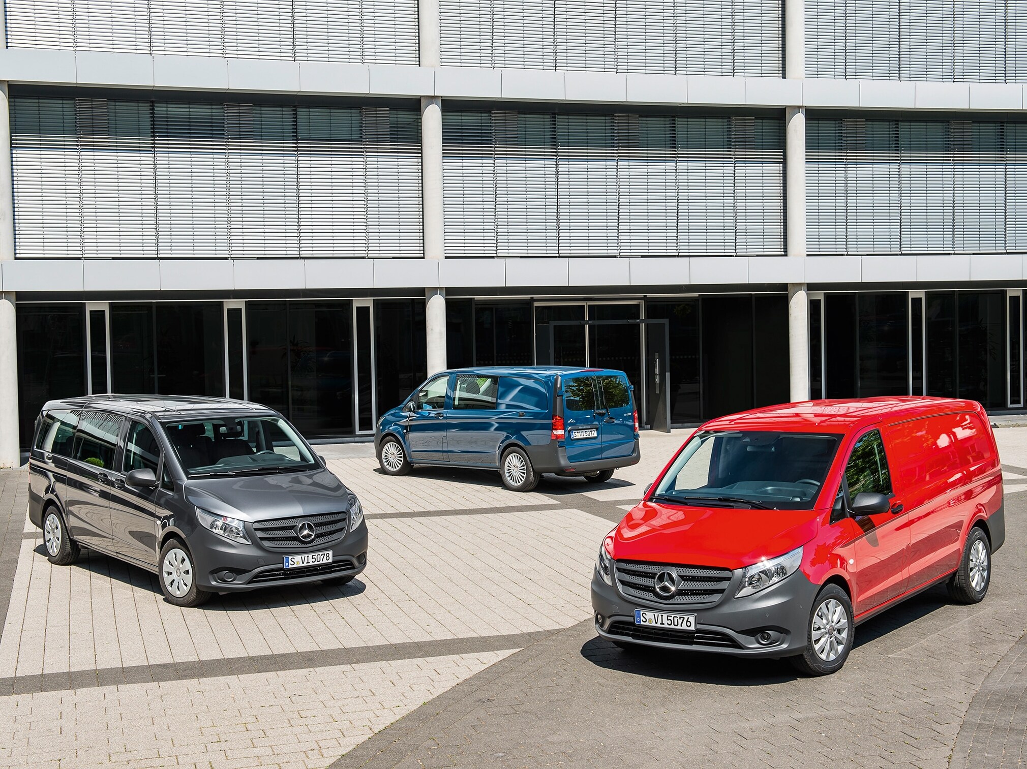 Több Mercedes-Benz Vito áll egy modern irodaház előtt