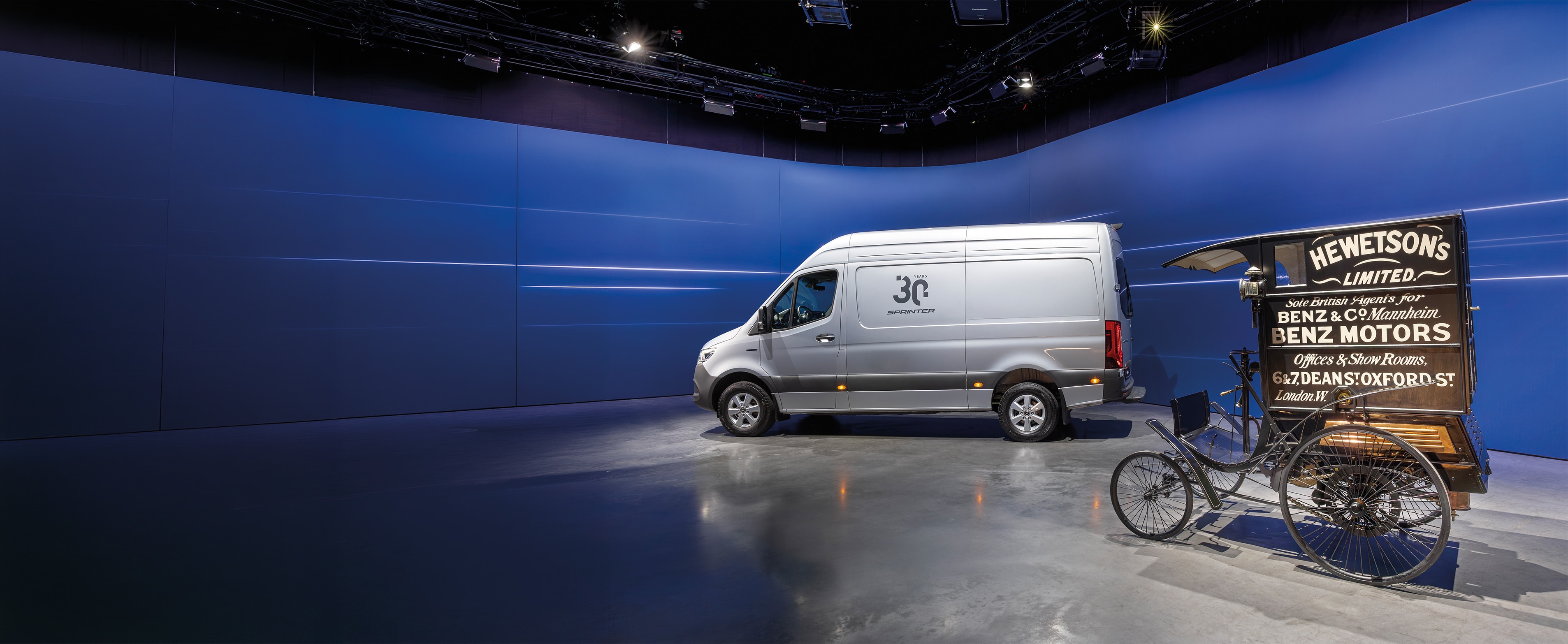 Történelem | Haszongépjárművek | Mercedes-Benz Mercedes-Benz Sprinter kishaszongépjármű és egy történelmi Benz áruszállító egy modern bemutatóteremben