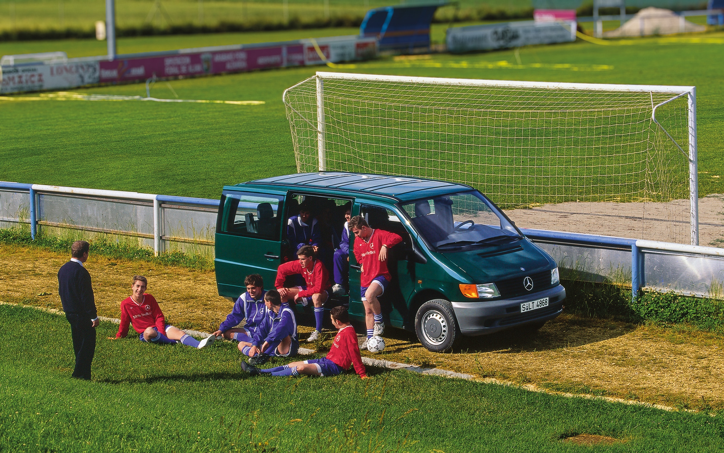 A Mercedes-Benz Vito első generációja | Haszongépjárművek történelme | Mercedes-Benz Az első generációs Vito a futballpálya mellett parkol, a csapat játékosai pedig a közelben tartózkodnak