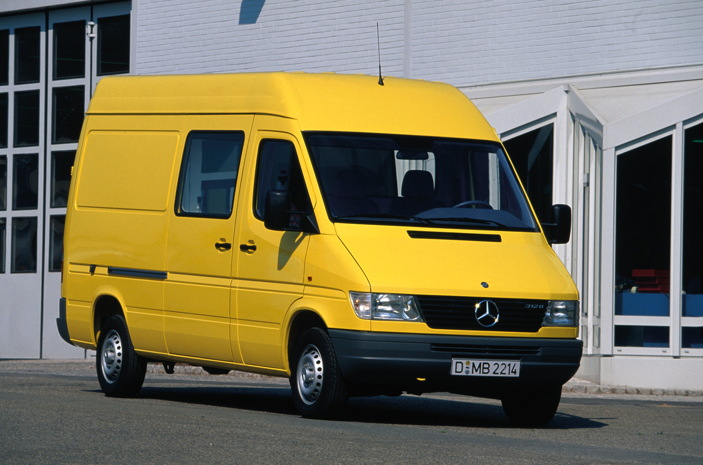 A Mercedes-Benz Sprinter első generációja | Haszongépjárművek történelme | Mercedes-Benz Egy első generációs Sprinter áll egy ipari épület előtt
