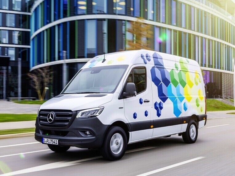Az eSprinter zárt áruszállító, a Mercedes-Benz elektromos kishaszongépjárműve, városi környezetben halad.