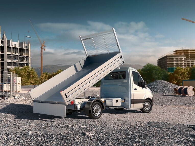 A Mercedes-Benz Sprinter platós gépjármű felállított platóval áll egy építési területen.