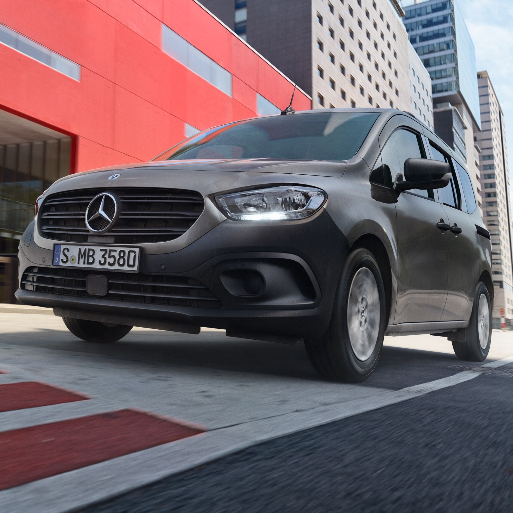 A Citan Tourer, a Mercedes-Benz kompakt személyszállító furgonja egy modern városi területen halad keresztül.