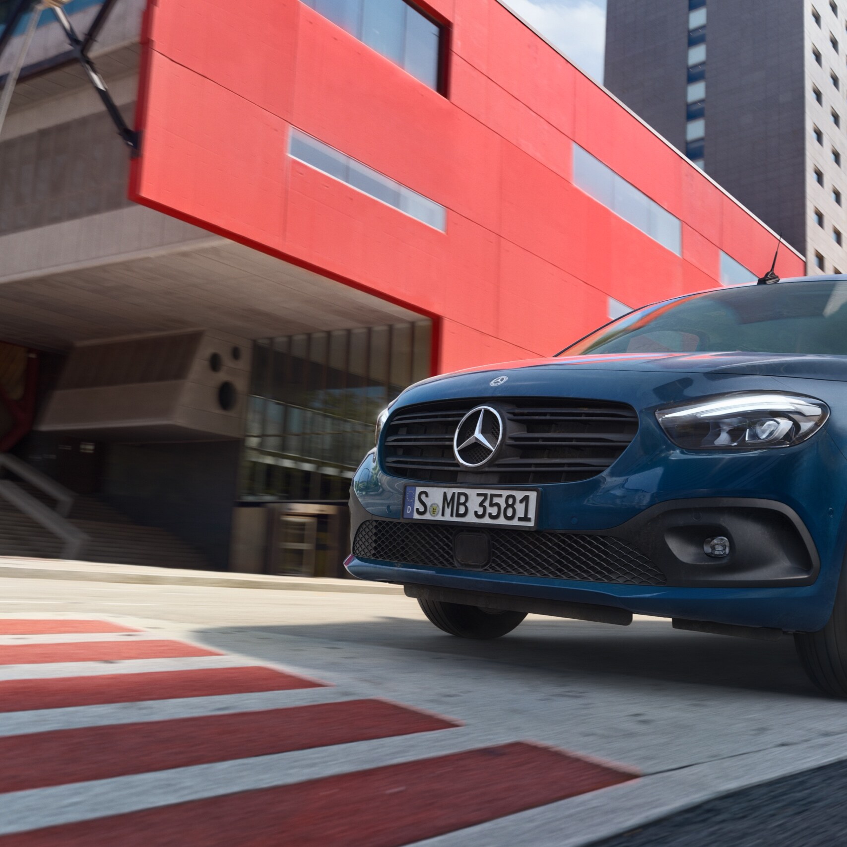 Az eCitan Tourer, a Mercedes-Benz elektromos személyszállító furgonja egy modern városi területen halad.