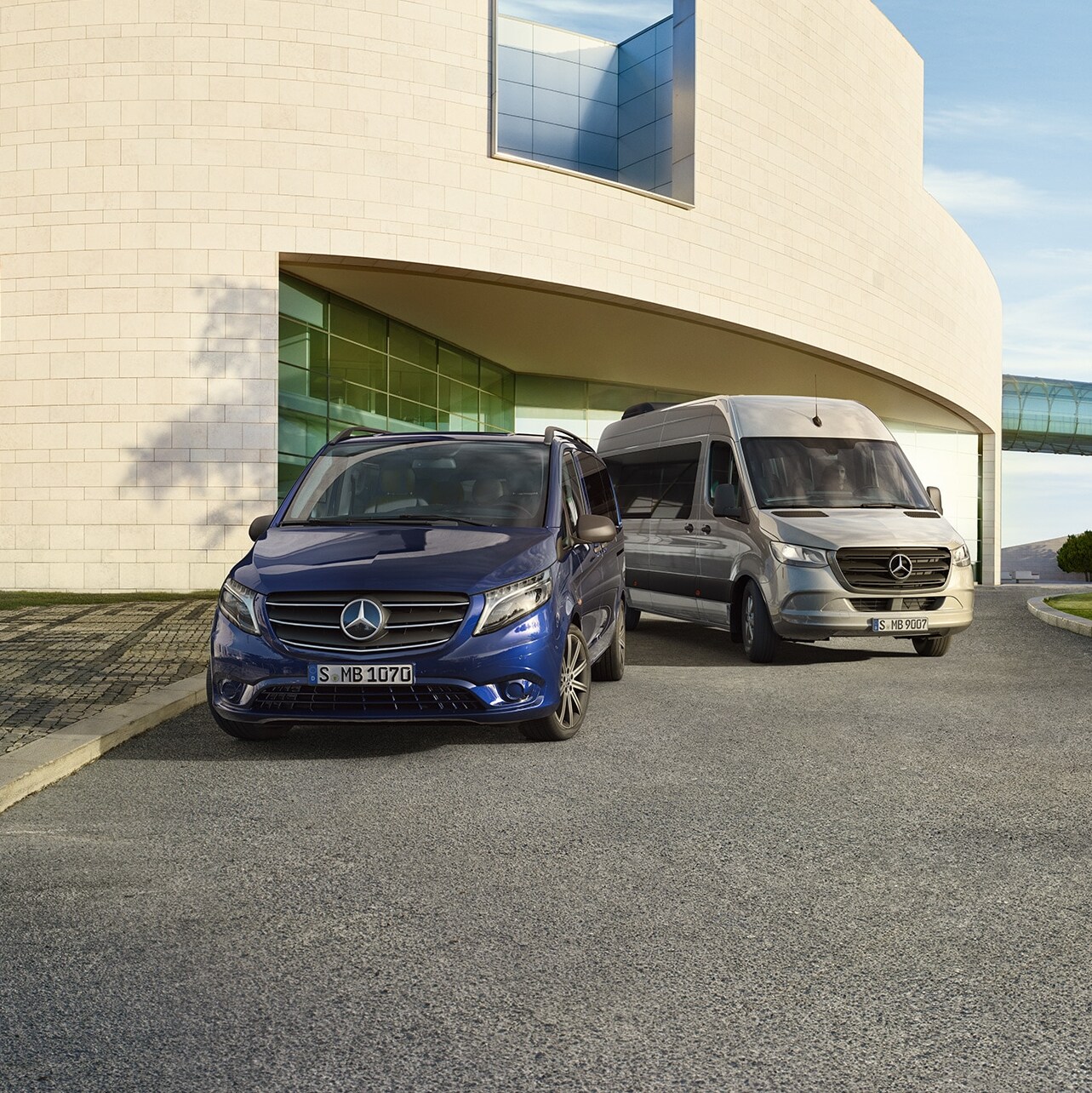 A Mercedes-Benz Vito Tourer és Sprinter Tourer egy modern ház előtt.