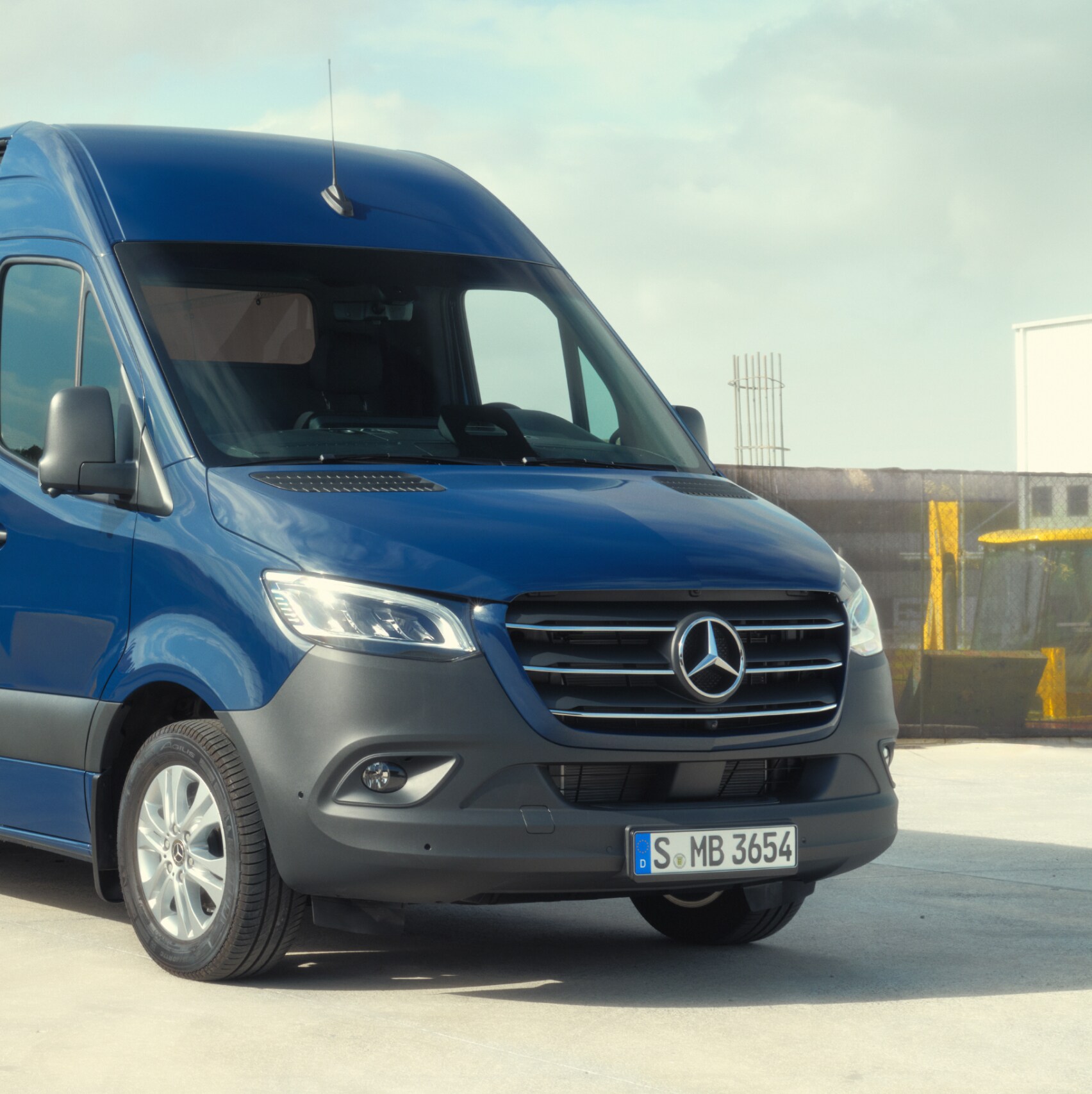A Mercedes-Benz Sprinter zárt áruszállító építőanyagok előtt.