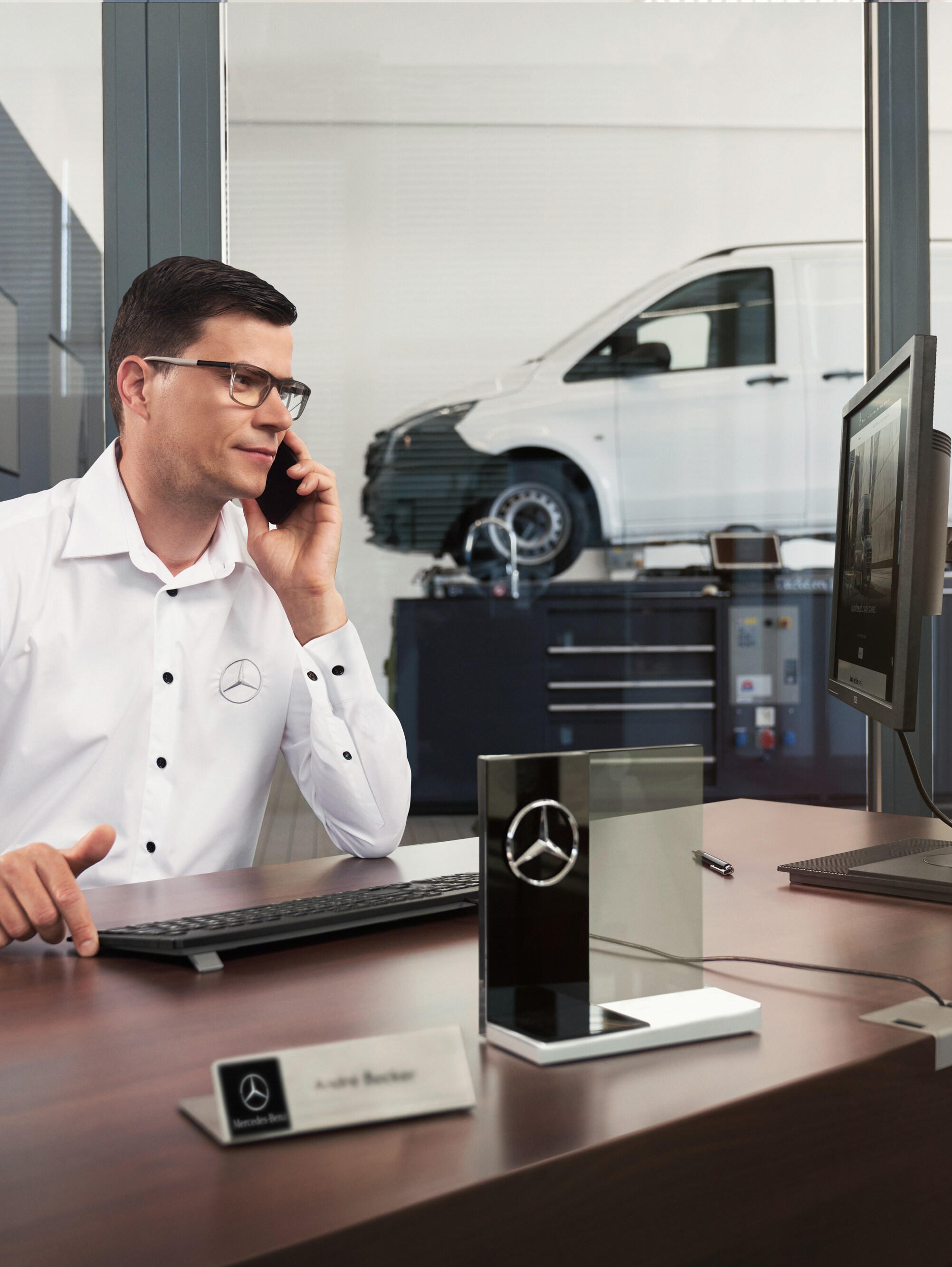 A Mercedes-Benz szerviztanácsadója telefonál egy műhelyben.