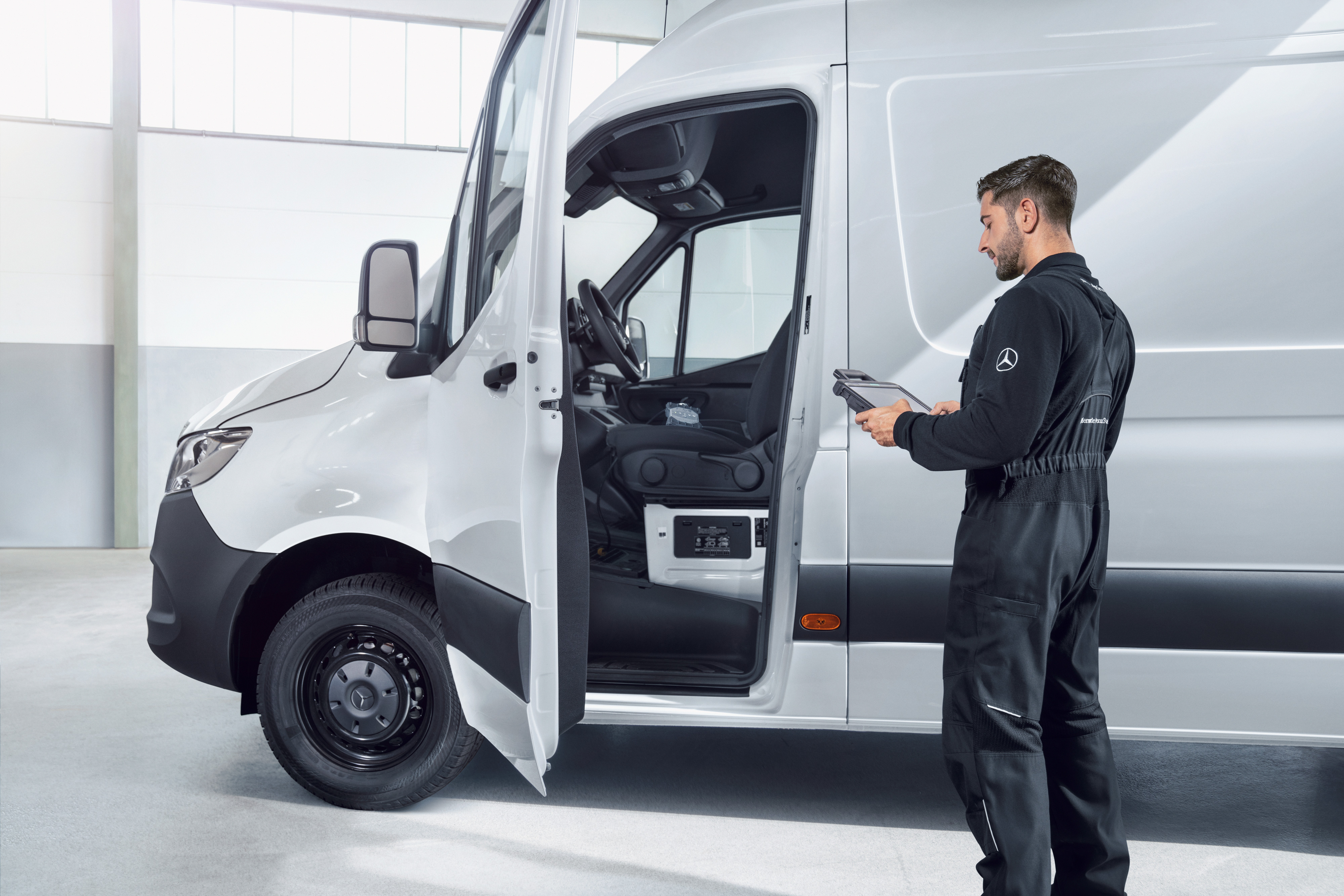 Mercedes-Benz | Kishaszongépjármű minőség Egy szerelő egy fehér Mercedes-Benz kishaszongépjárművet ellenőriz egy tablettel.