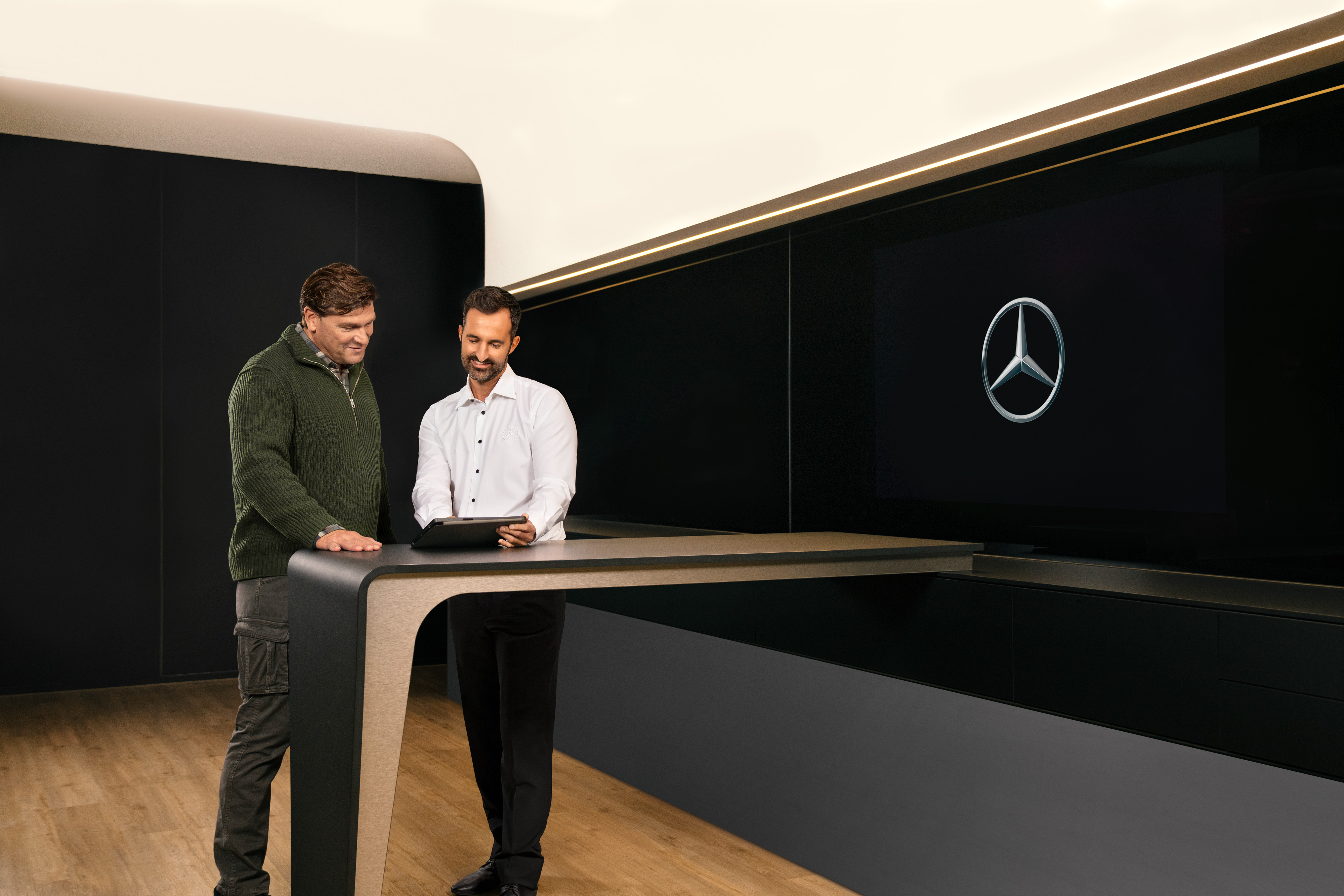 Mercedes-Benz | Szervizszerződések kishaszongépjárművekhez Két férfi konzultál egy asztal körül állva, egy iPadet nézve.