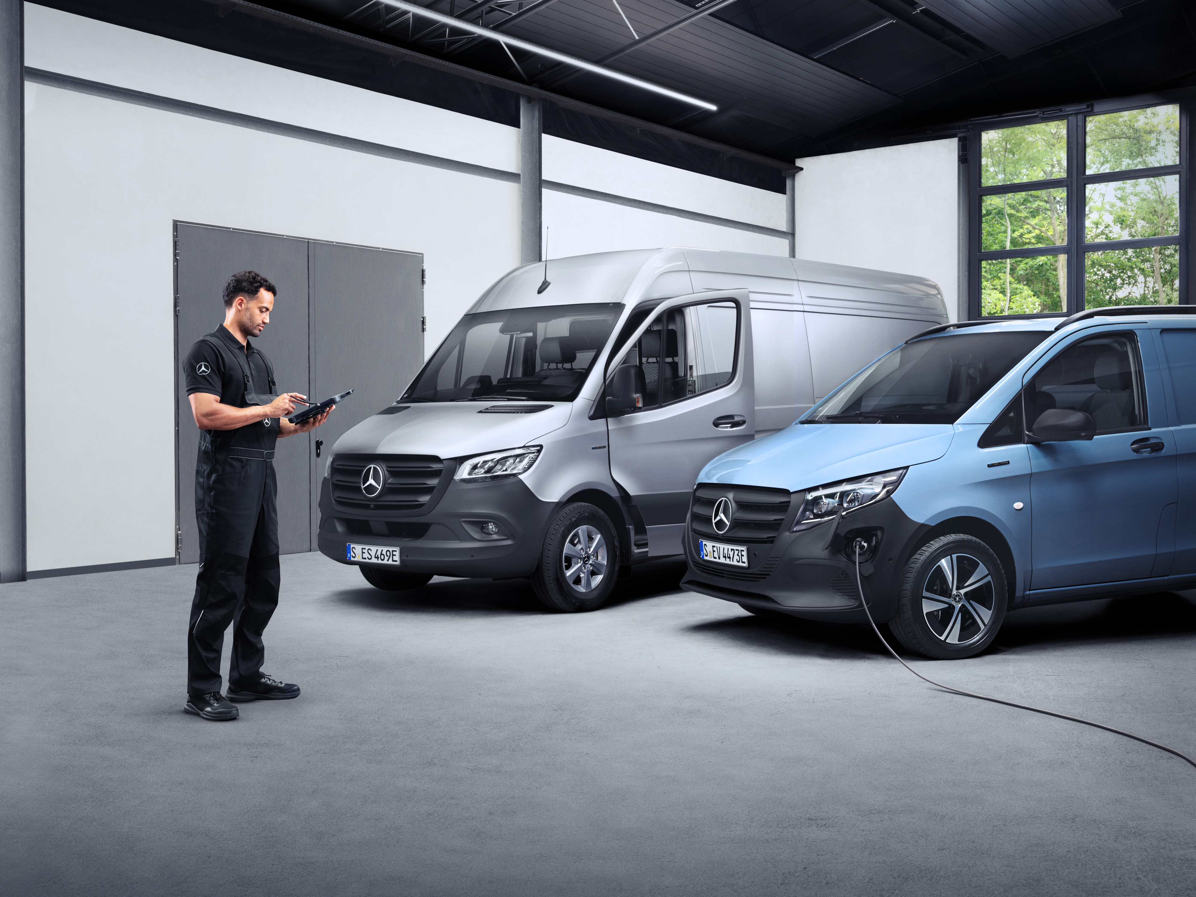 Mercedes-Benz | Van ServiceCare Egy technikus két e-transzporter előtt egy tableten