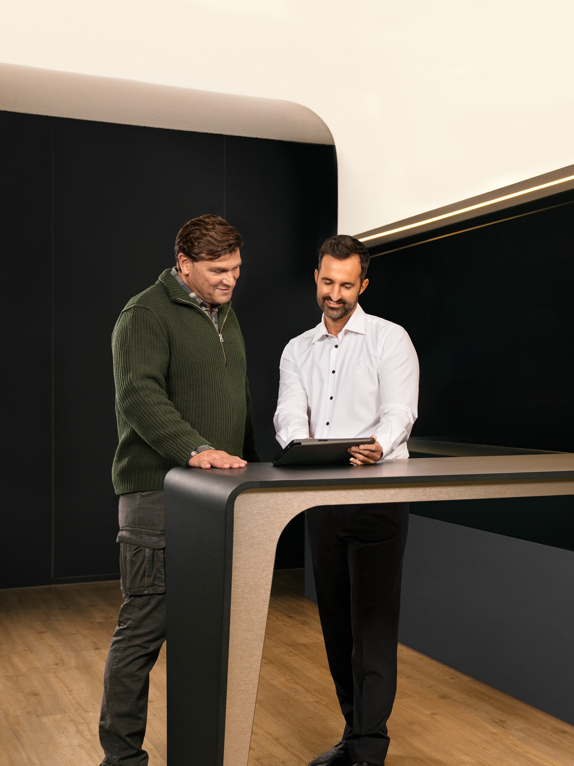 Két férfi beszélget a Mercedes-Benz kishaszongépjármű szolgáltatásokról egy tablet felett.