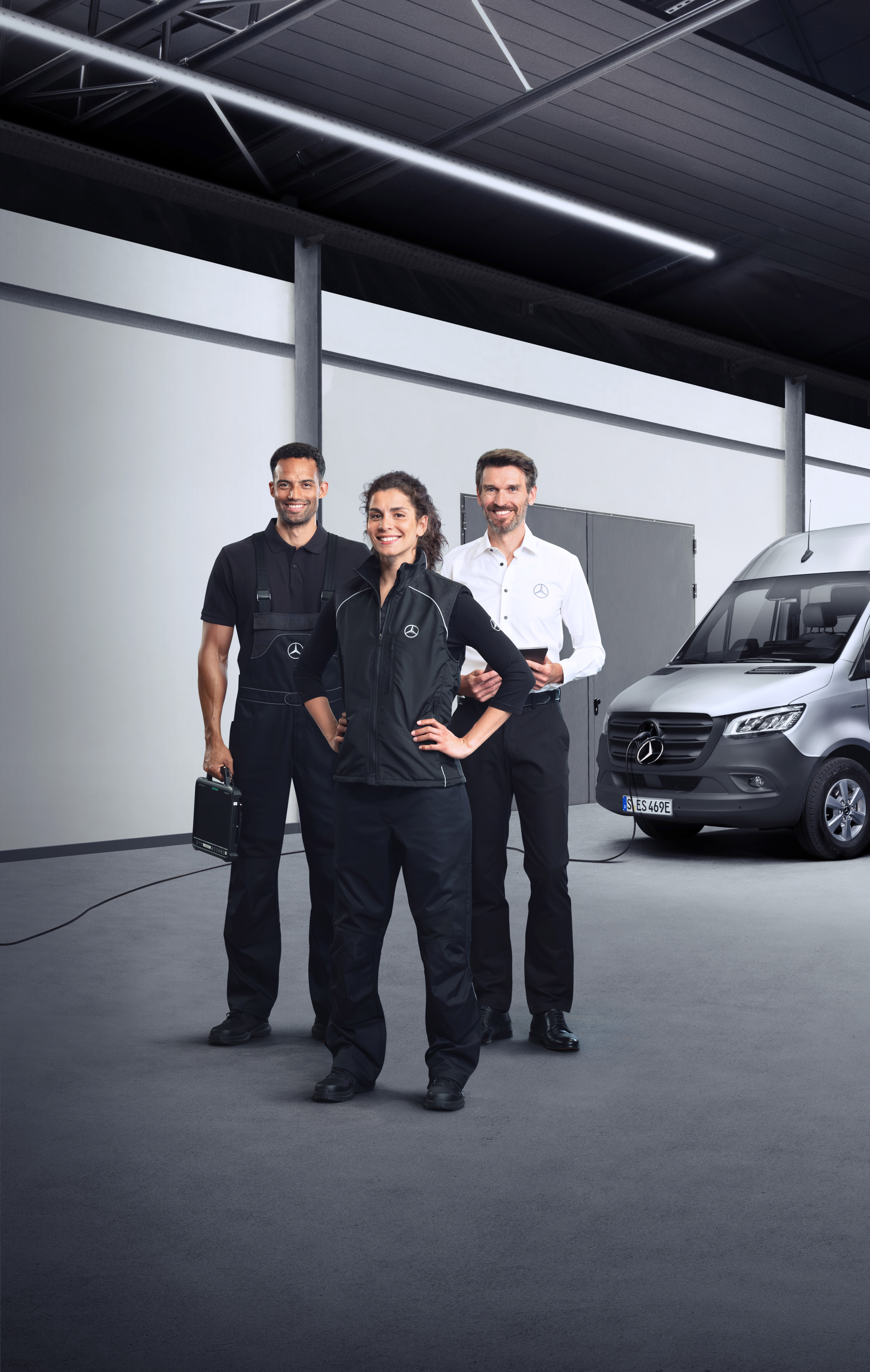 Mercedes-Benz | Szolgáltatások áttekintése | Elektromos járművek szolgáltatásai Három alkalmazott áll egy ezüstszínű Mercedes-Benz eSprinter előtt, csatlakoztatott töltőkábellel.