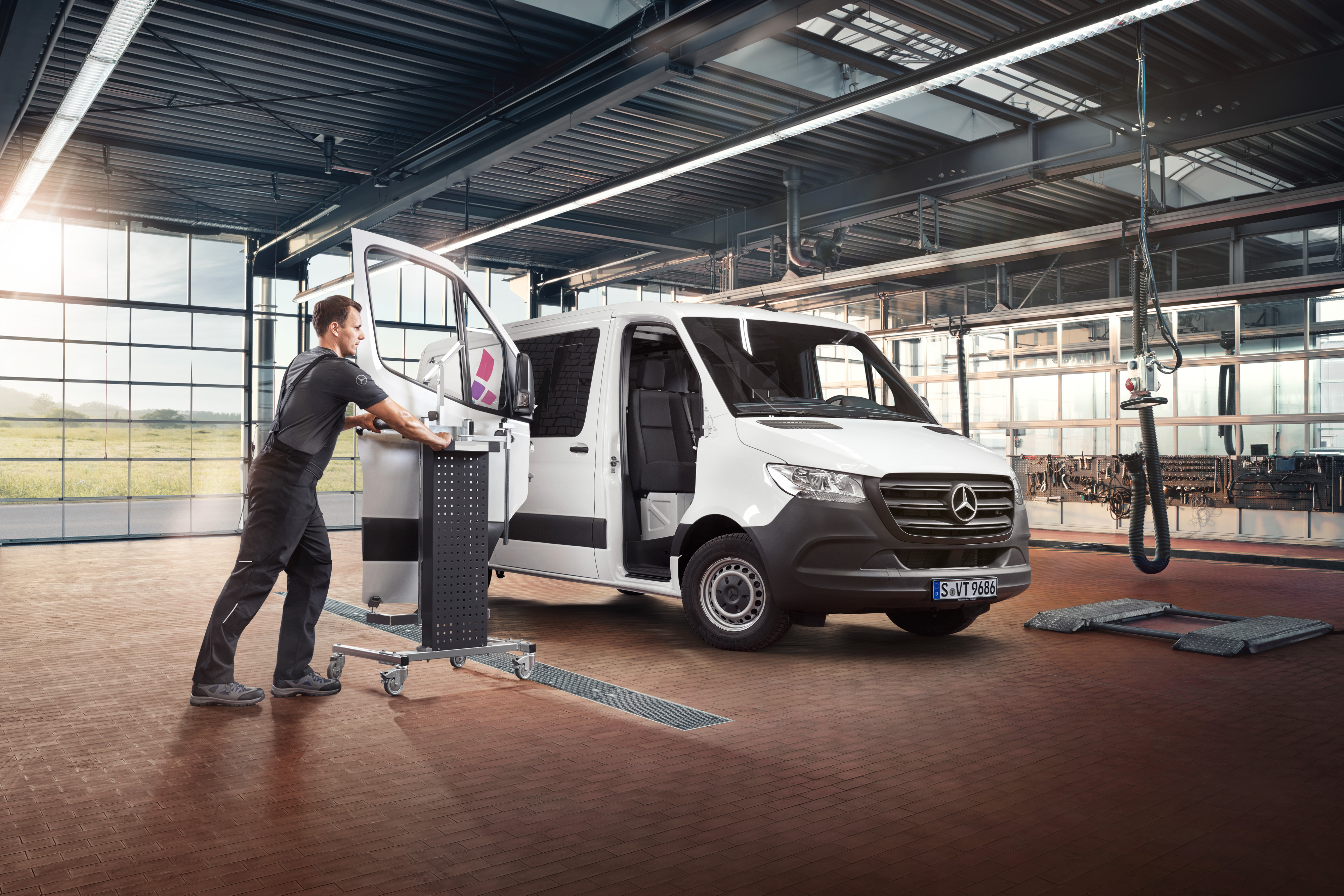 Mercedes-Benz | Szolgáltatások áttekintése | Javítás Egy technikus leveszi egy fehér Mercedes-Benz Sprinter utasoldali ajtóját.