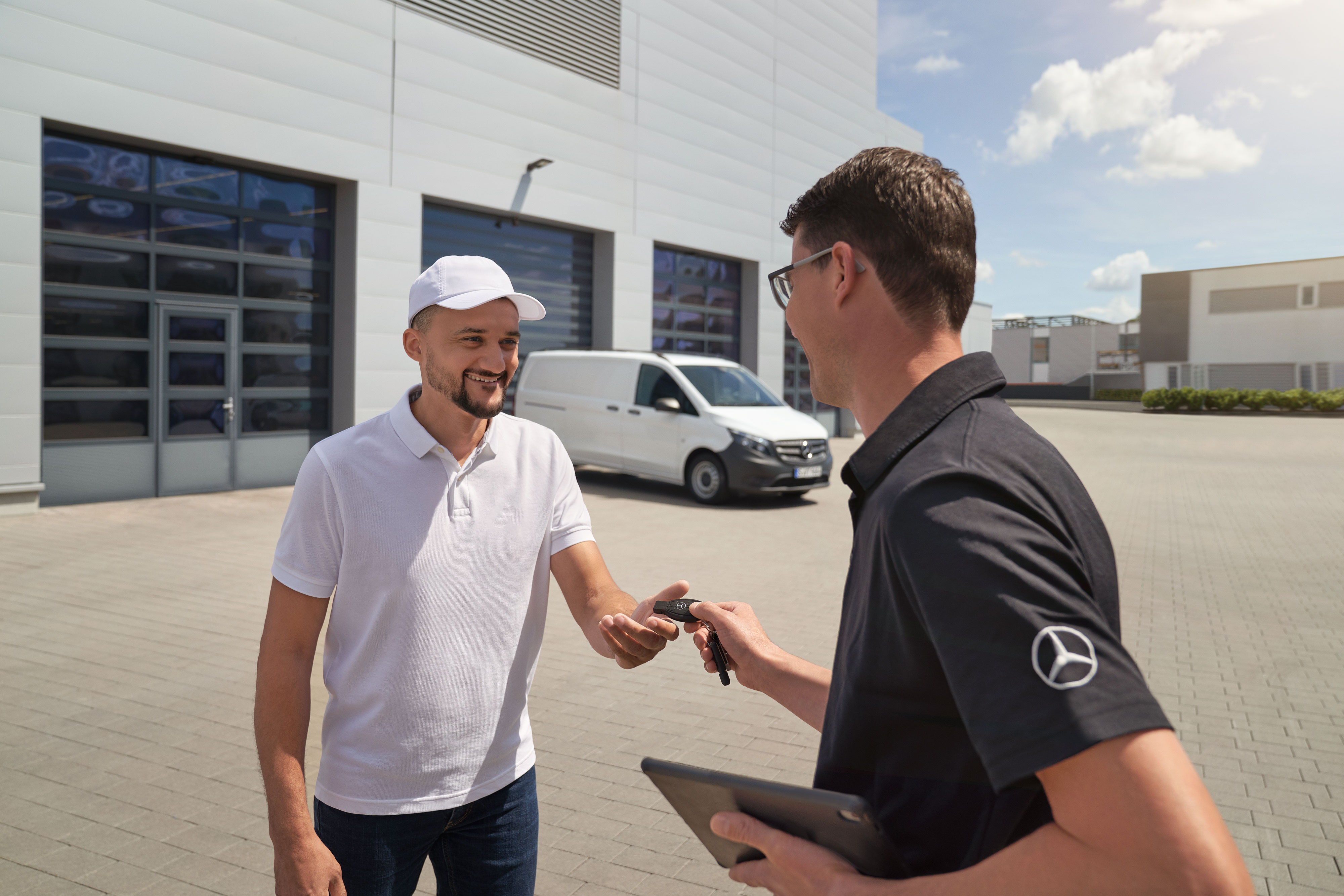 Mercedes-Benz | Van ServiceCare | További opciók Egy szerelő átadja a kulcsot egy ügyfélnek, a háttérben egy fehér Mercedes-Benz Vito transzporter.