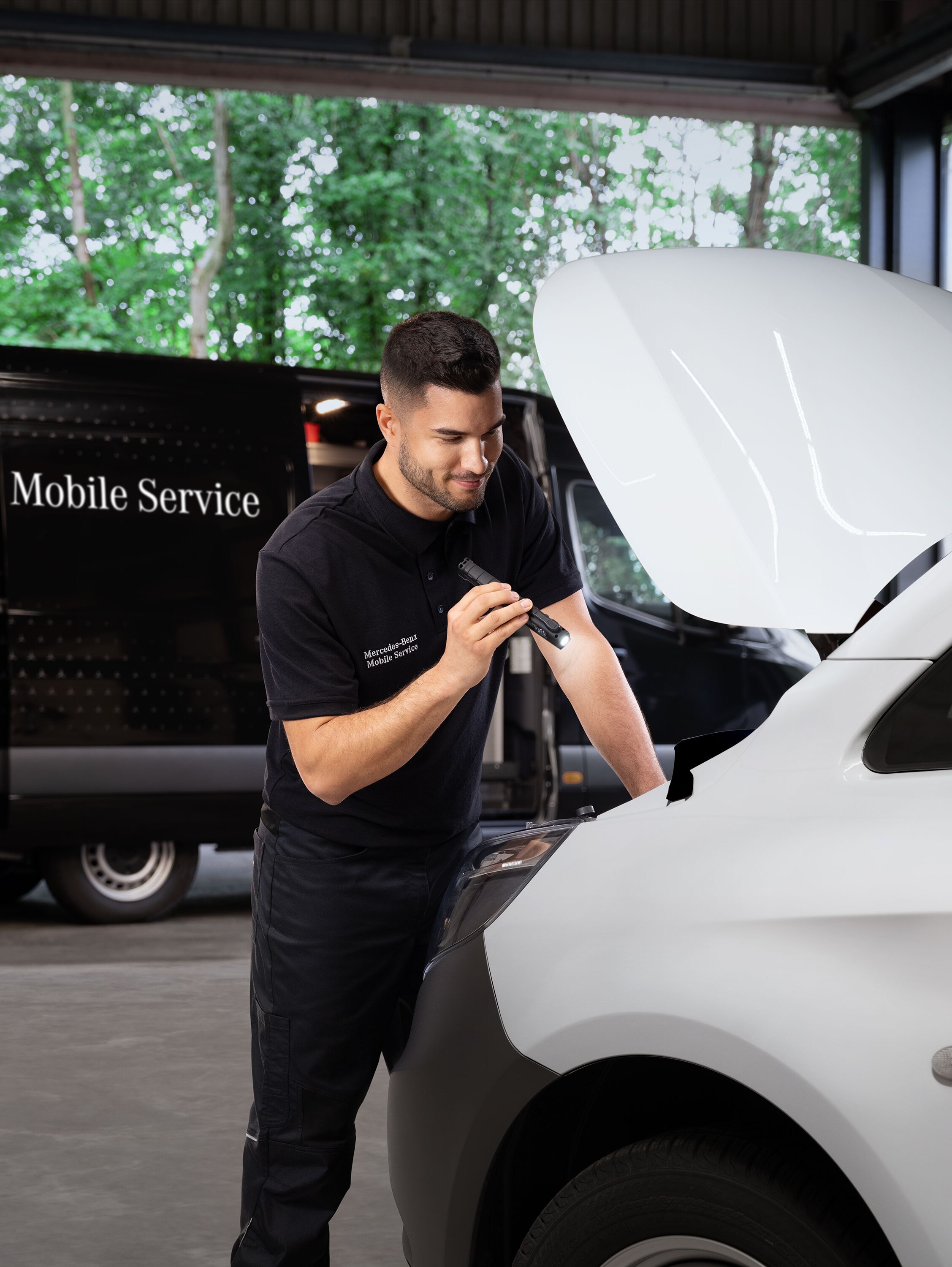 Technikus vizsgálja egy fehér Mercedes-Benz kishaszongépjármű motorját.