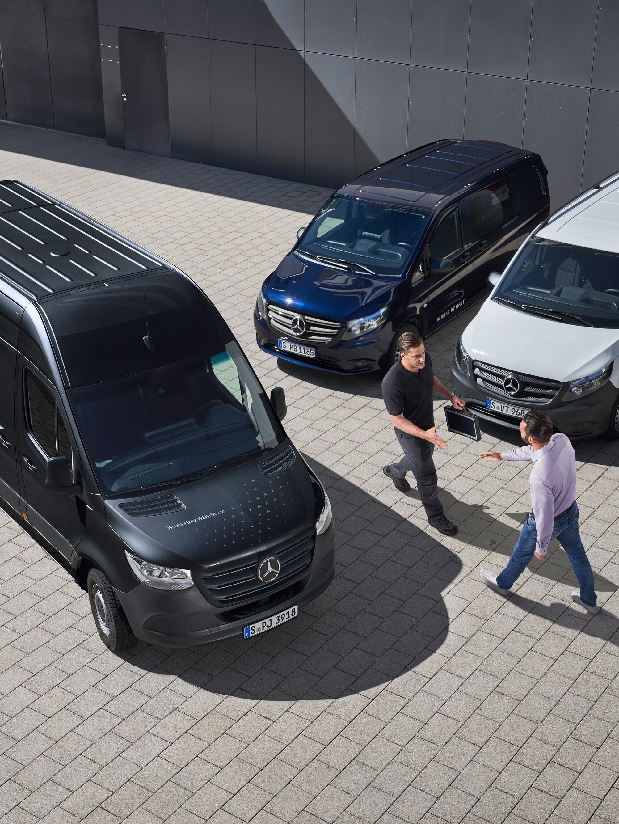 Két férfi köszönti egymást a Mercedes-Benz kishaszongépjárművek között.