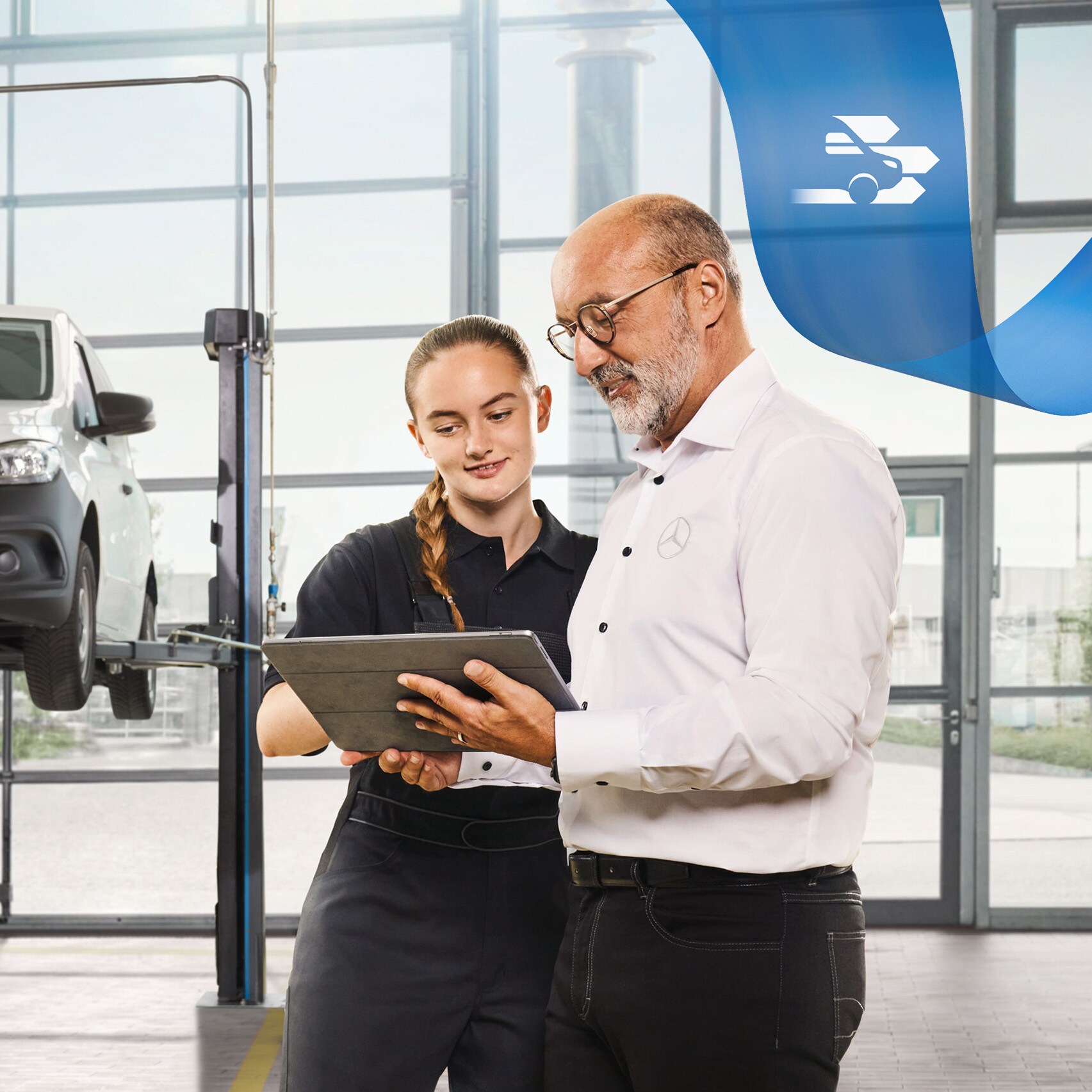 Két alkalmazott a műhelyben egy felemelt Mercedes-Benz kishaszongépjármű szervizeléséről beszélget.