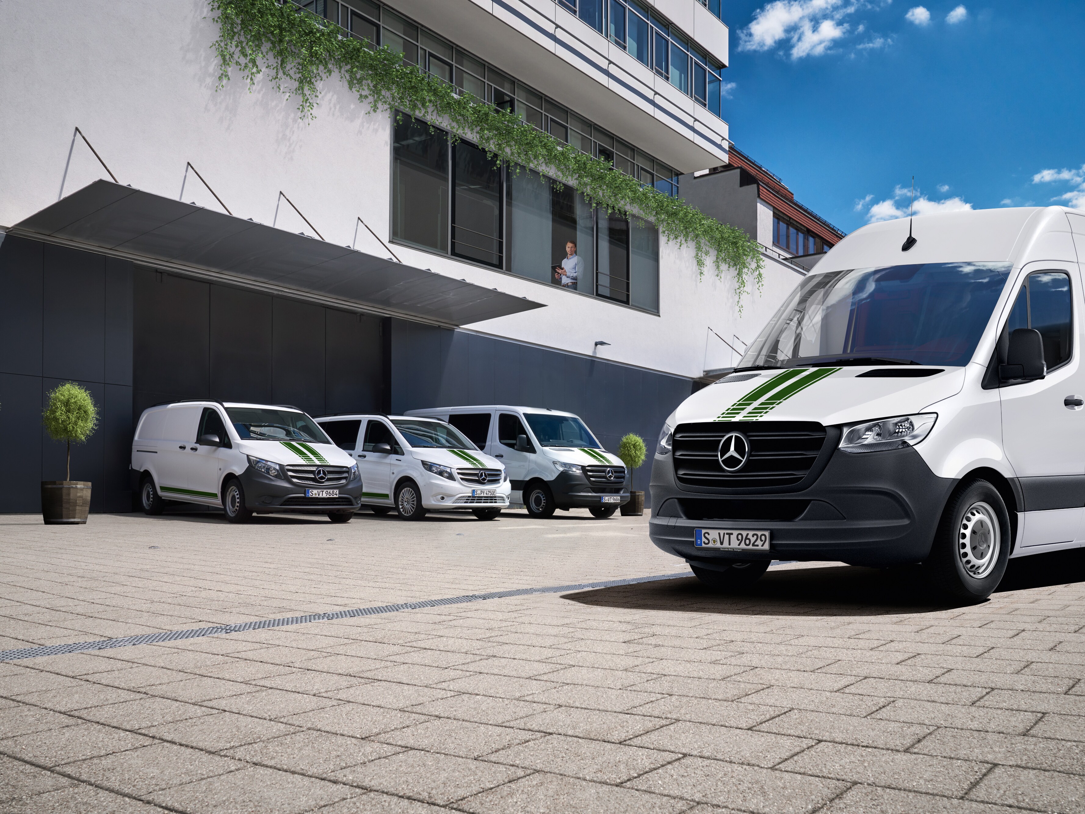 Mercedes-Benz kishaszongépjárművek flottája egy épület előtt, a digitális flottafelügyeletet szimbolizálva.