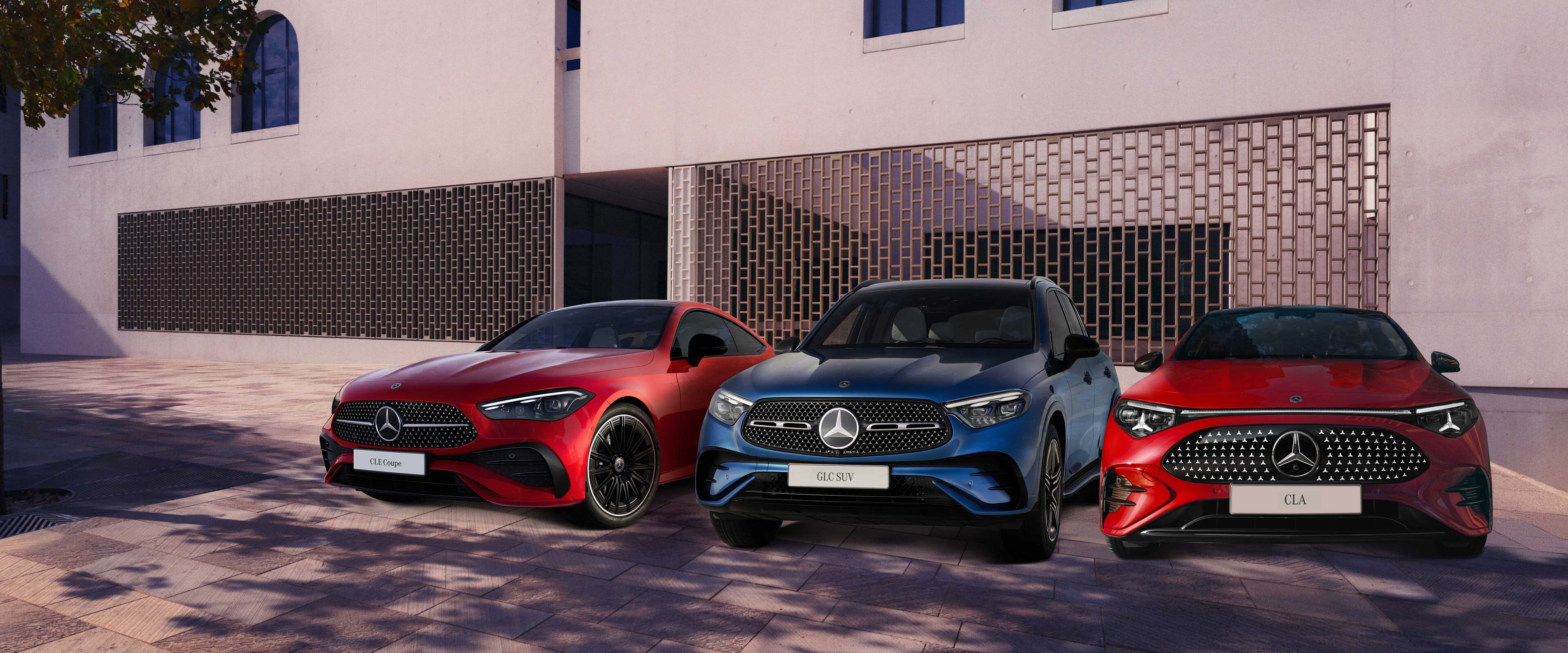 Három Mercedes-Benz modell parkol az épület előtt.