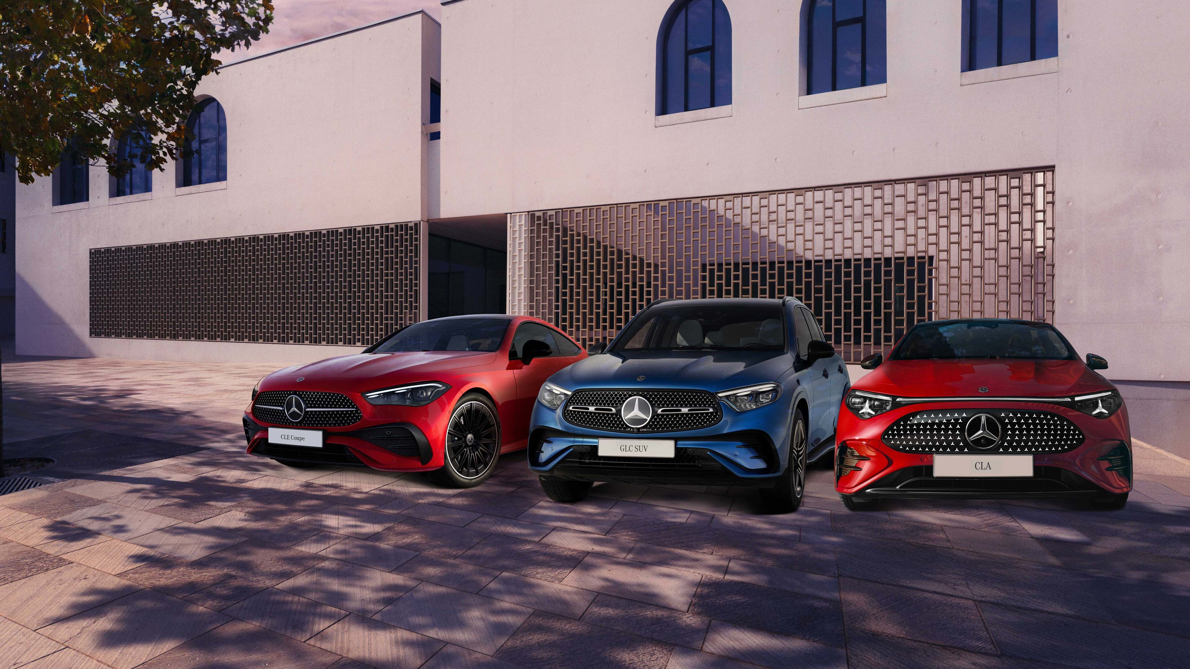 Három Mercedes-Benz modell parkol az épület előtt.