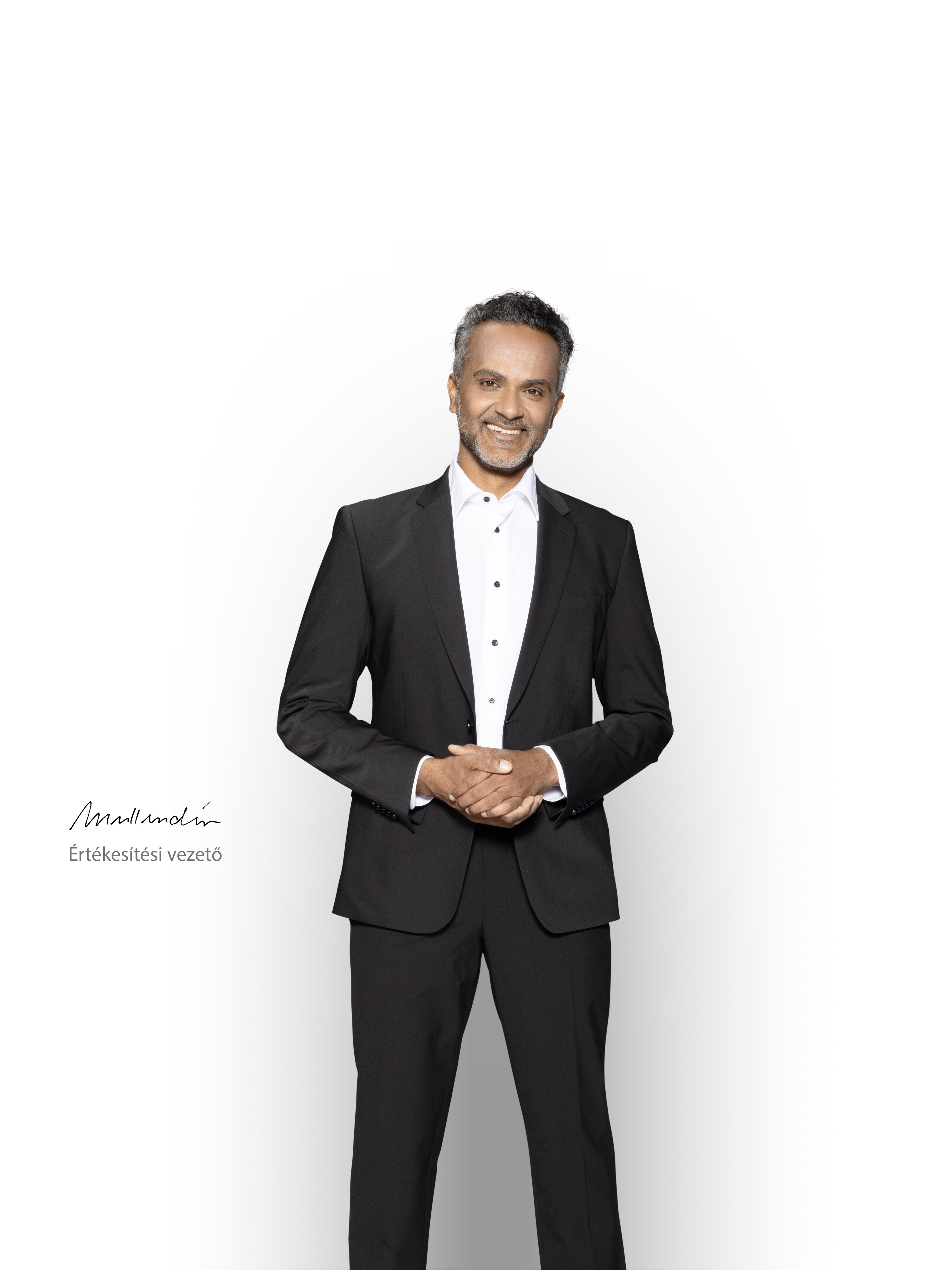 Egy hozzáértő értékesítési vezető áll és mosolyog, hogy támogatást biztosítson az Ön Mercedes-Benz elektromos kishaszongépjárművéhez.