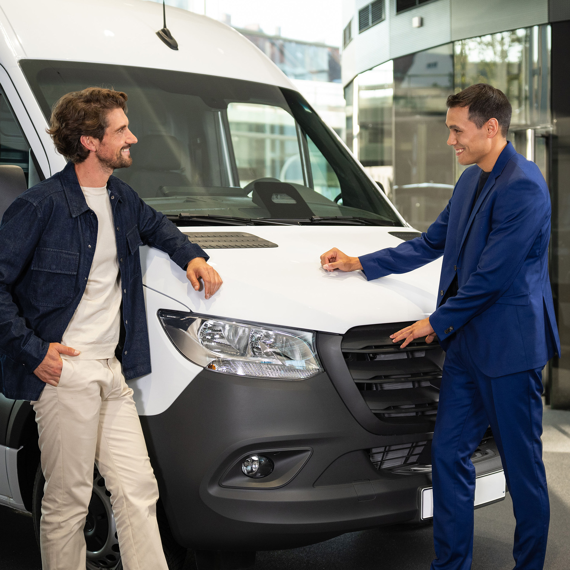 Új gépkocsik | Lízing és finanszírozás | Pénzügyi szolgáltatások | Mercedes-Benz Egy férfi beszél a Mercedes-Benz márkakereskedővel a fehér eSprinter Van-ről